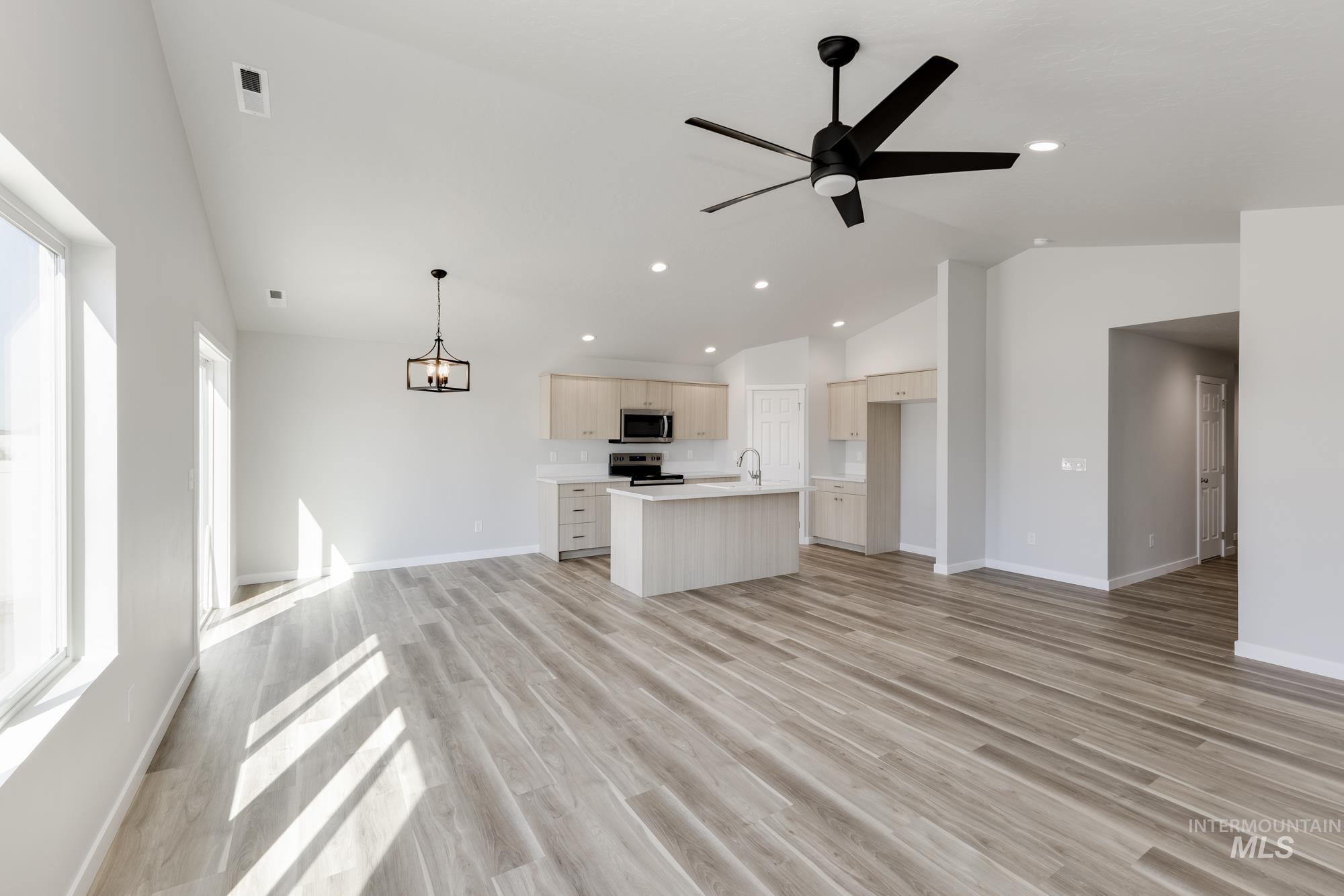 Unfurnished living room with light wood-style flooring, a chandelier, ceiling fan, recessed lighting, and high vaulted ceiling