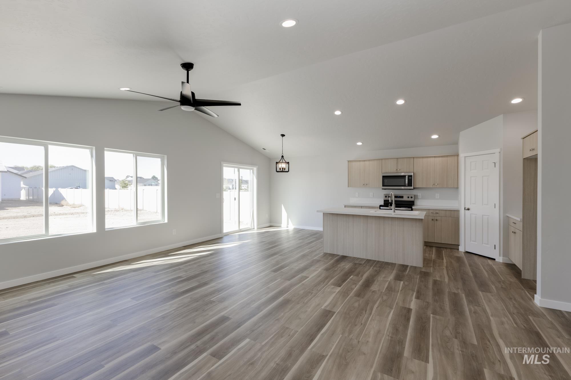 Kitchen with open floor plan, light countertops, lofted ceiling, a kitchen island with sink, and recessed lighting