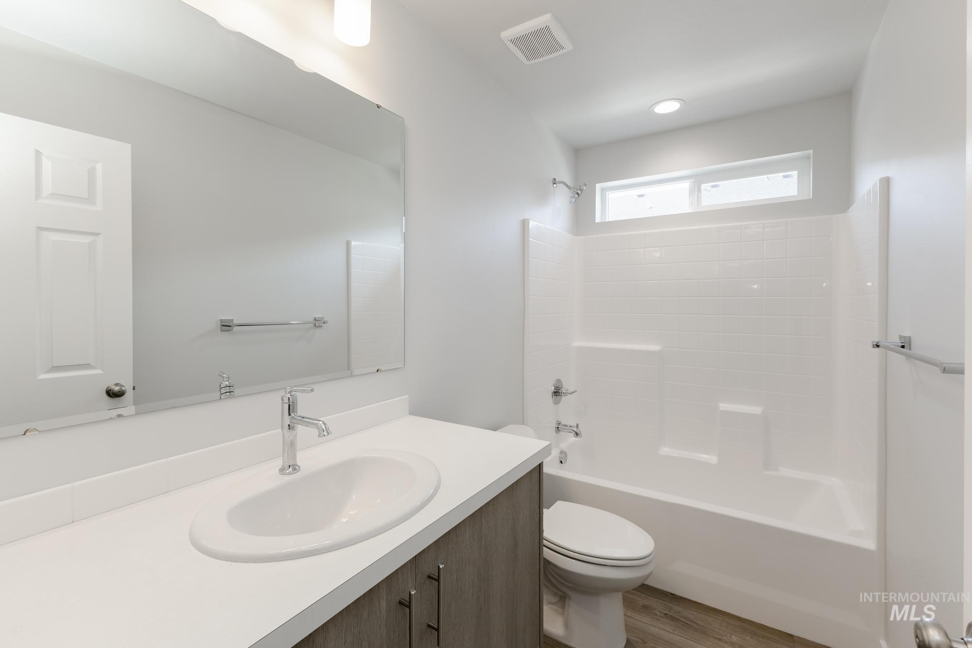 Bathroom with bathtub / shower combination, vanity, and wood finished floors