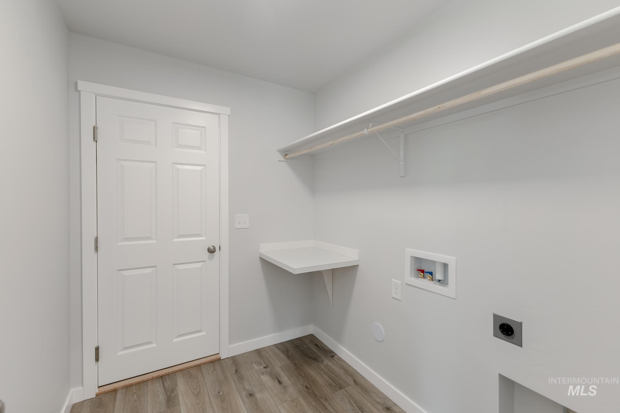 Washroom with hookup for a washing machine, light wood-type flooring, and electric dryer hookup