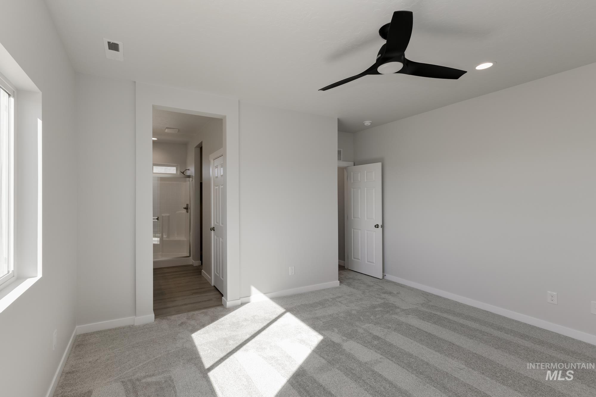 Unfurnished bedroom featuring light colored carpet, a ceiling fan, ensuite bath, and recessed lighting