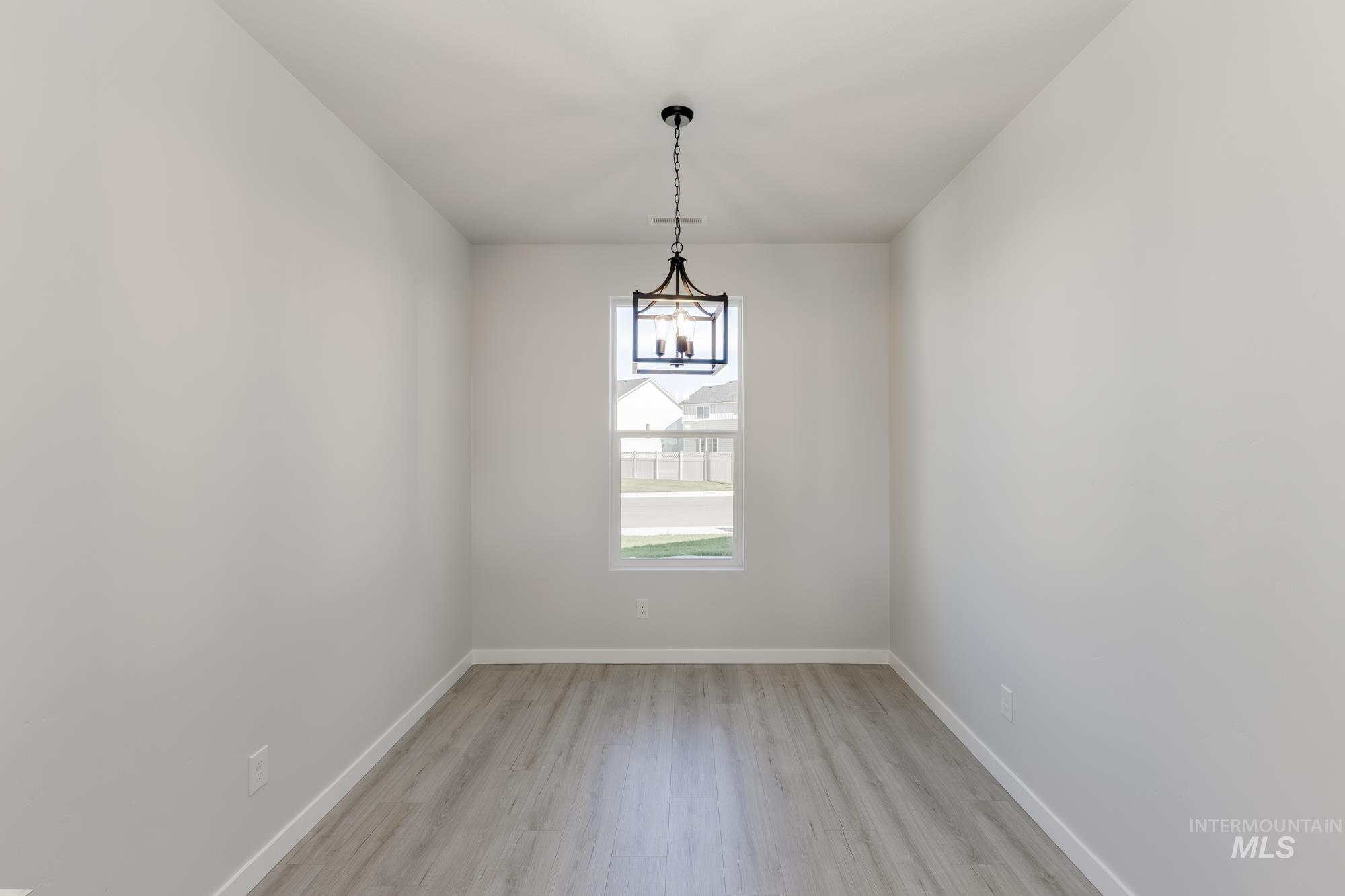 Unfurnished room with light wood finished floors and a chandelier
