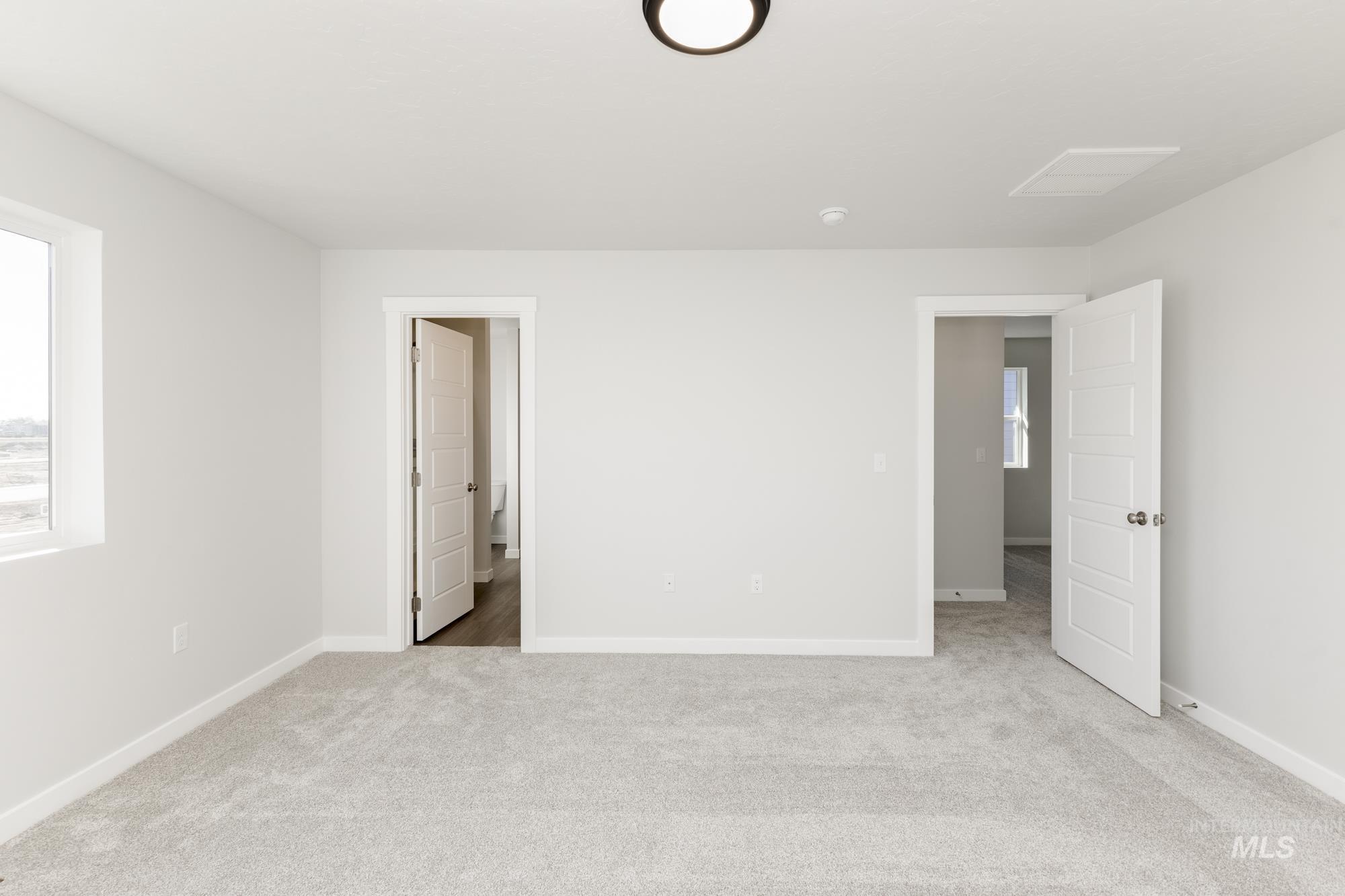 Unfurnished bedroom with light colored carpet and multiple windows