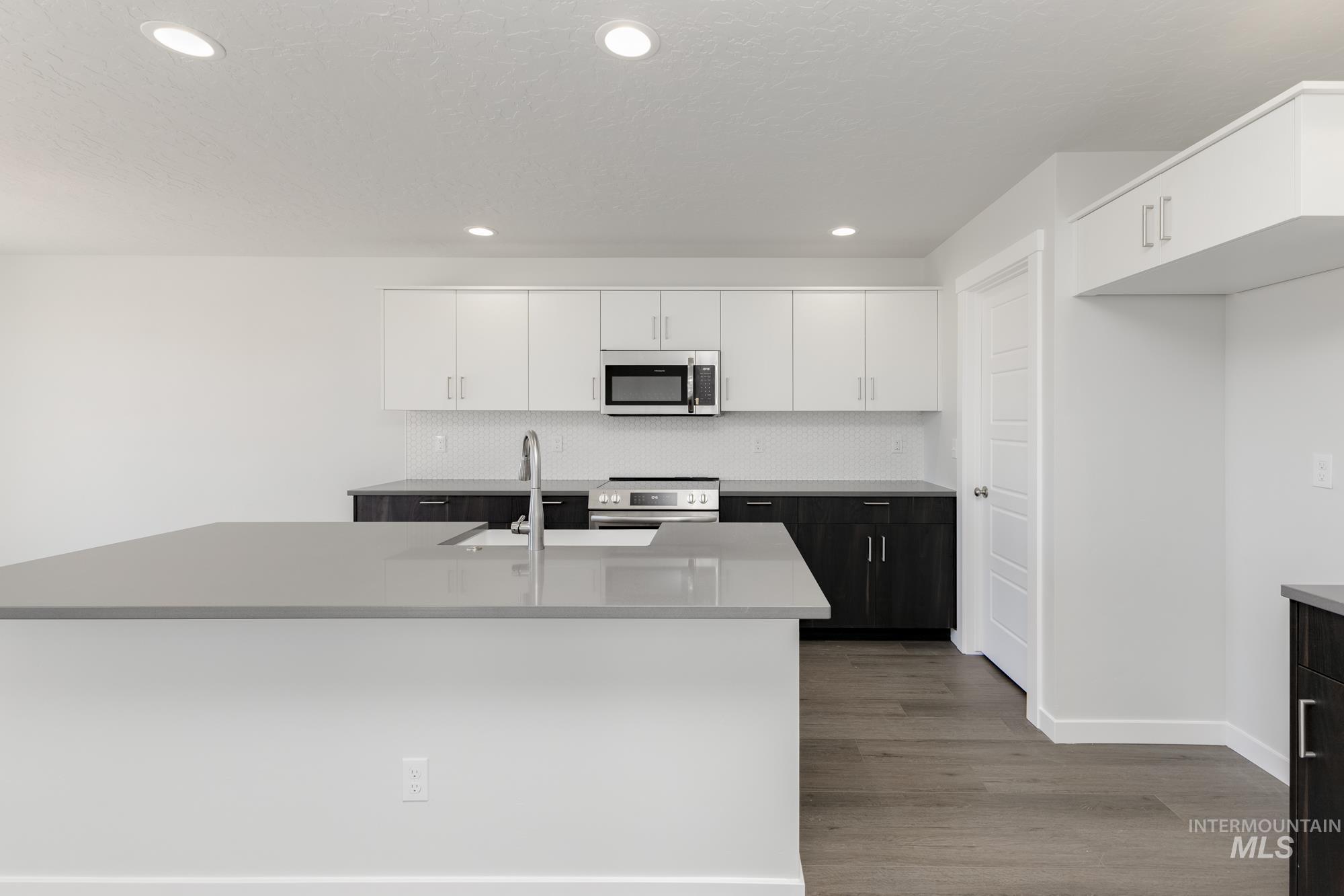 Kitchen with white cabinets, recessed lighting, stainless steel appliances, light wood finished floors, and decorative backsplash