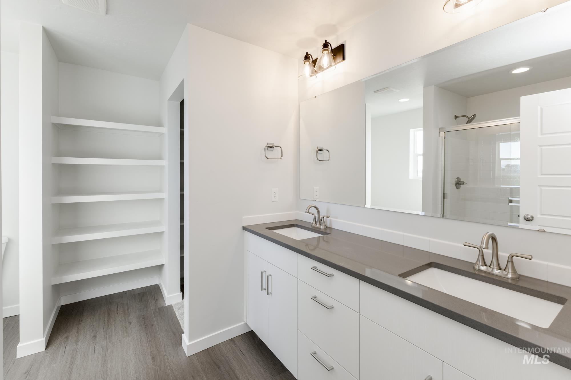 Full bathroom with a stall shower, dark wood-type flooring, double vanity, a walk in closet, and recessed lighting