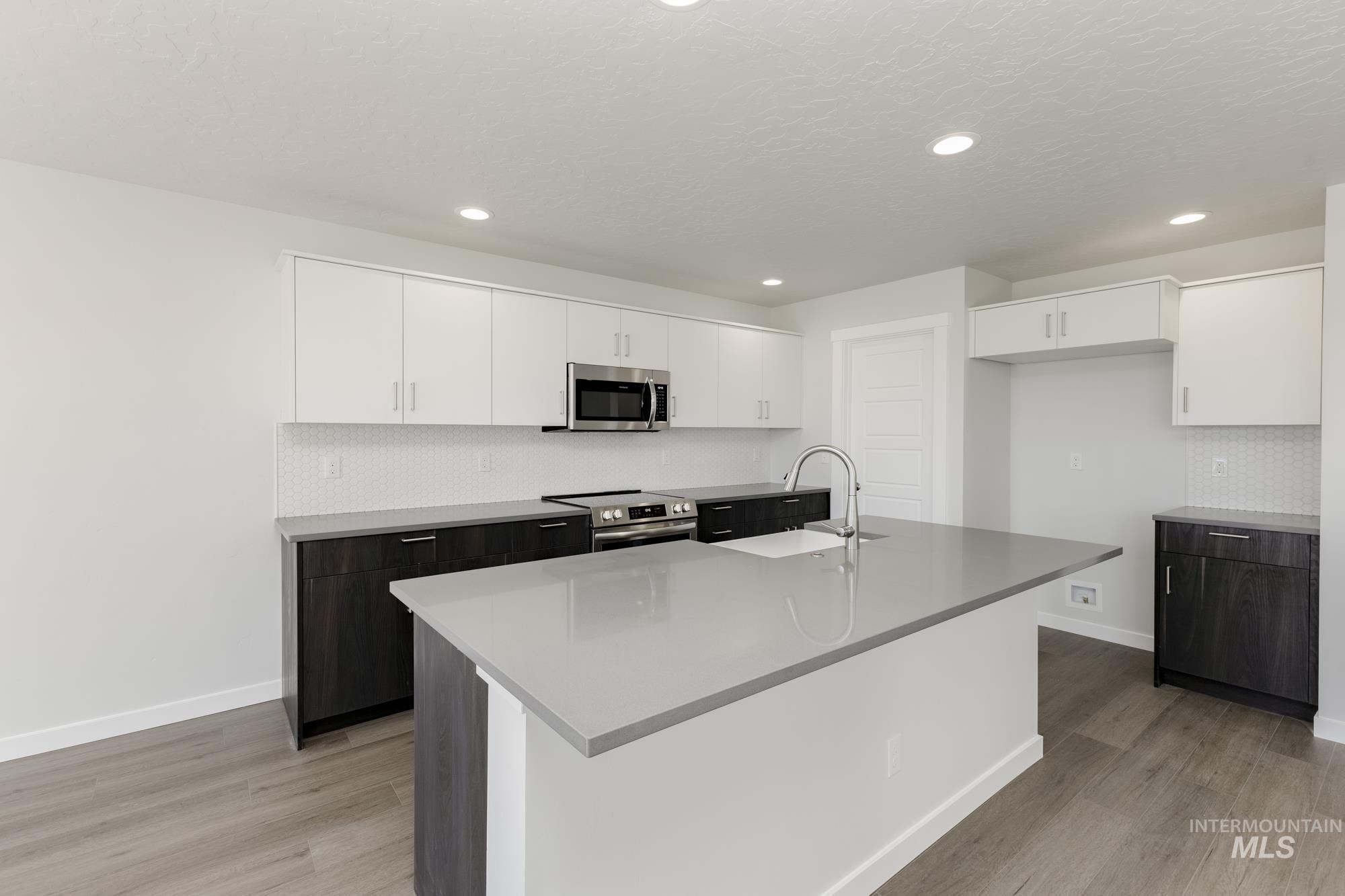 Kitchen with white cabinetry, decorative backsplash, stainless steel appliances, light wood finished floors, and recessed lighting