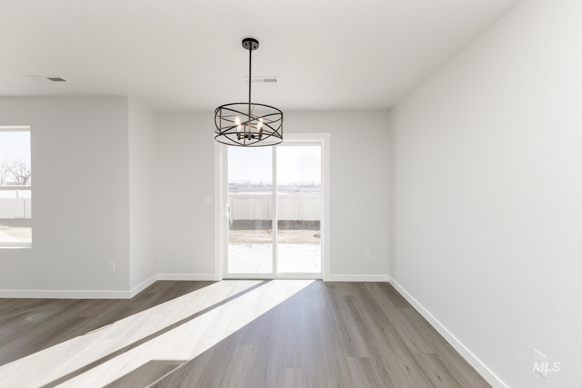 Unfurnished dining area featuring wood finished floors and a chandelier