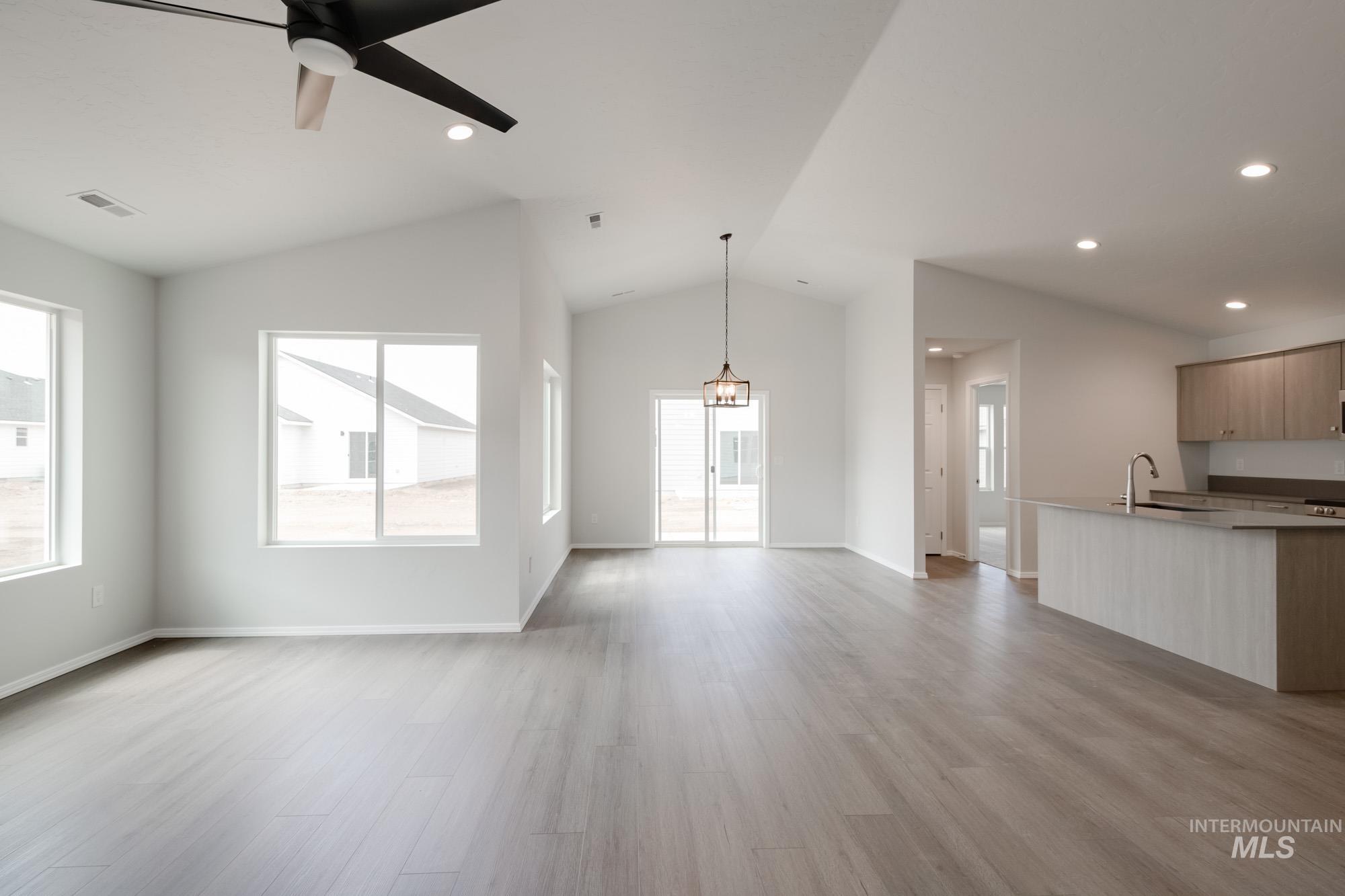 Unfurnished living room featuring light wood-type flooring, recessed lighting, healthy amount of natural light, a ceiling fan, and vaulted ceiling