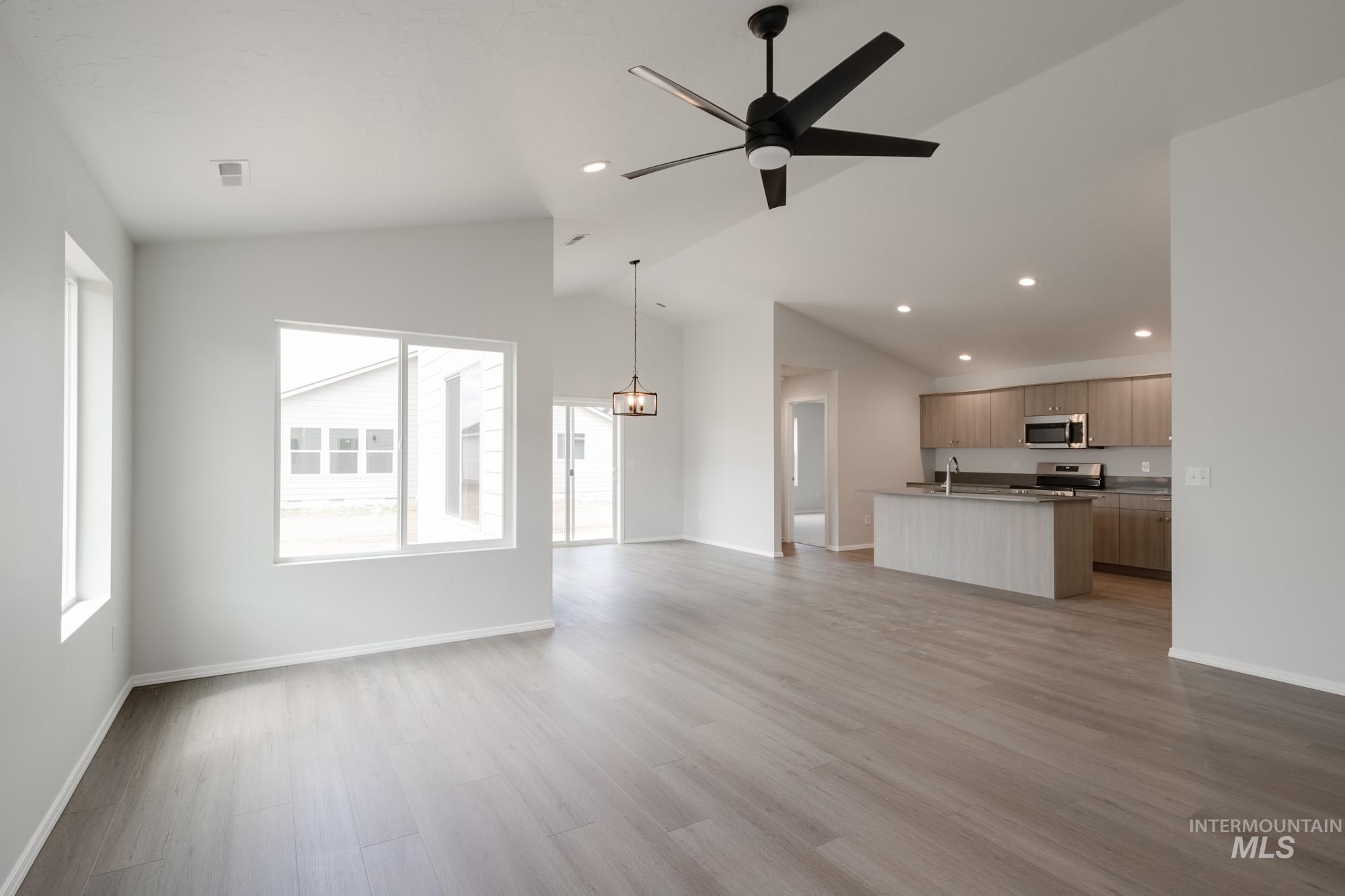 Unfurnished living room with vaulted ceiling, light wood-style flooring, recessed lighting, and a ceiling fan