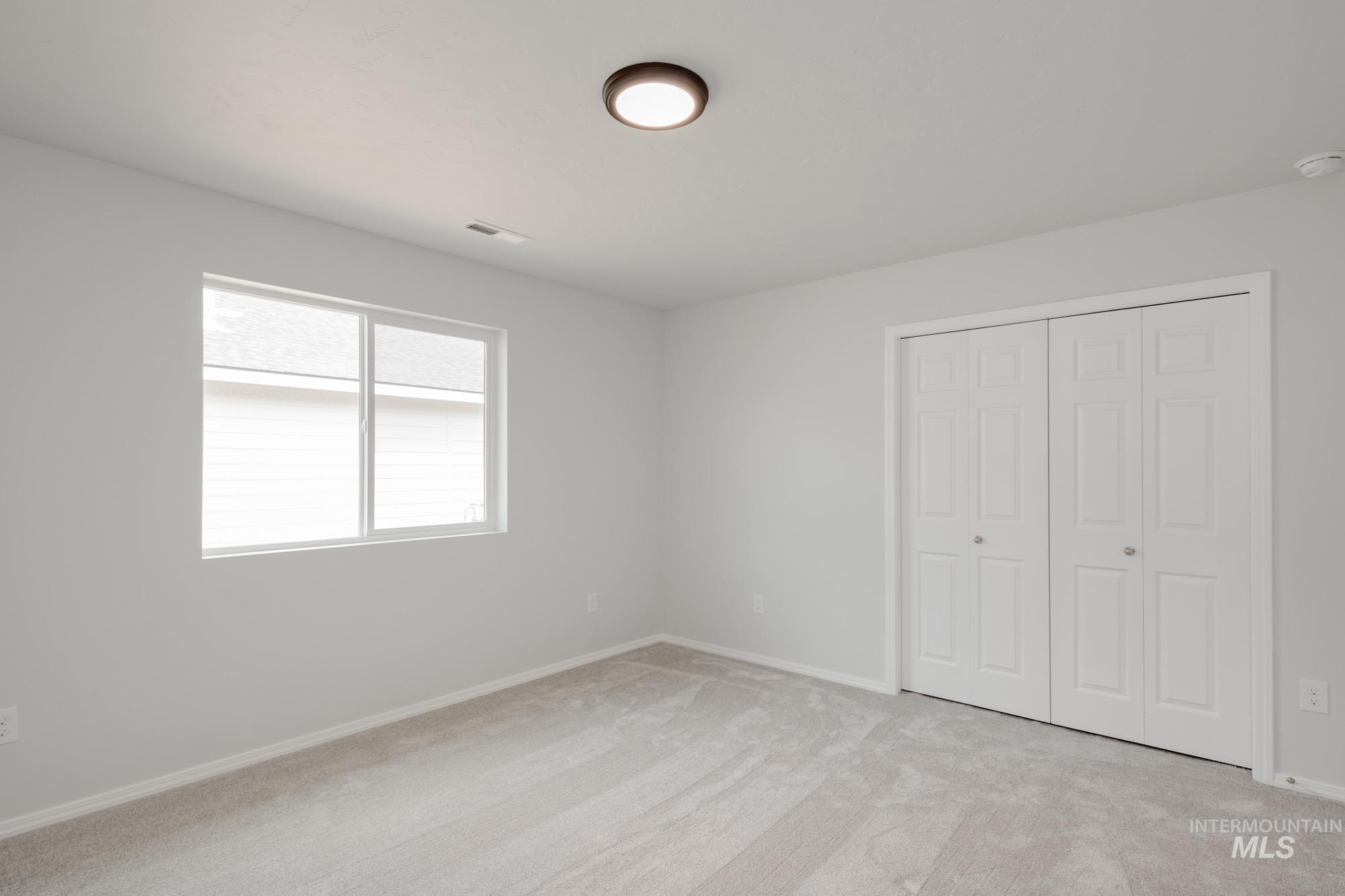 Unfurnished bedroom with light carpet and a closet