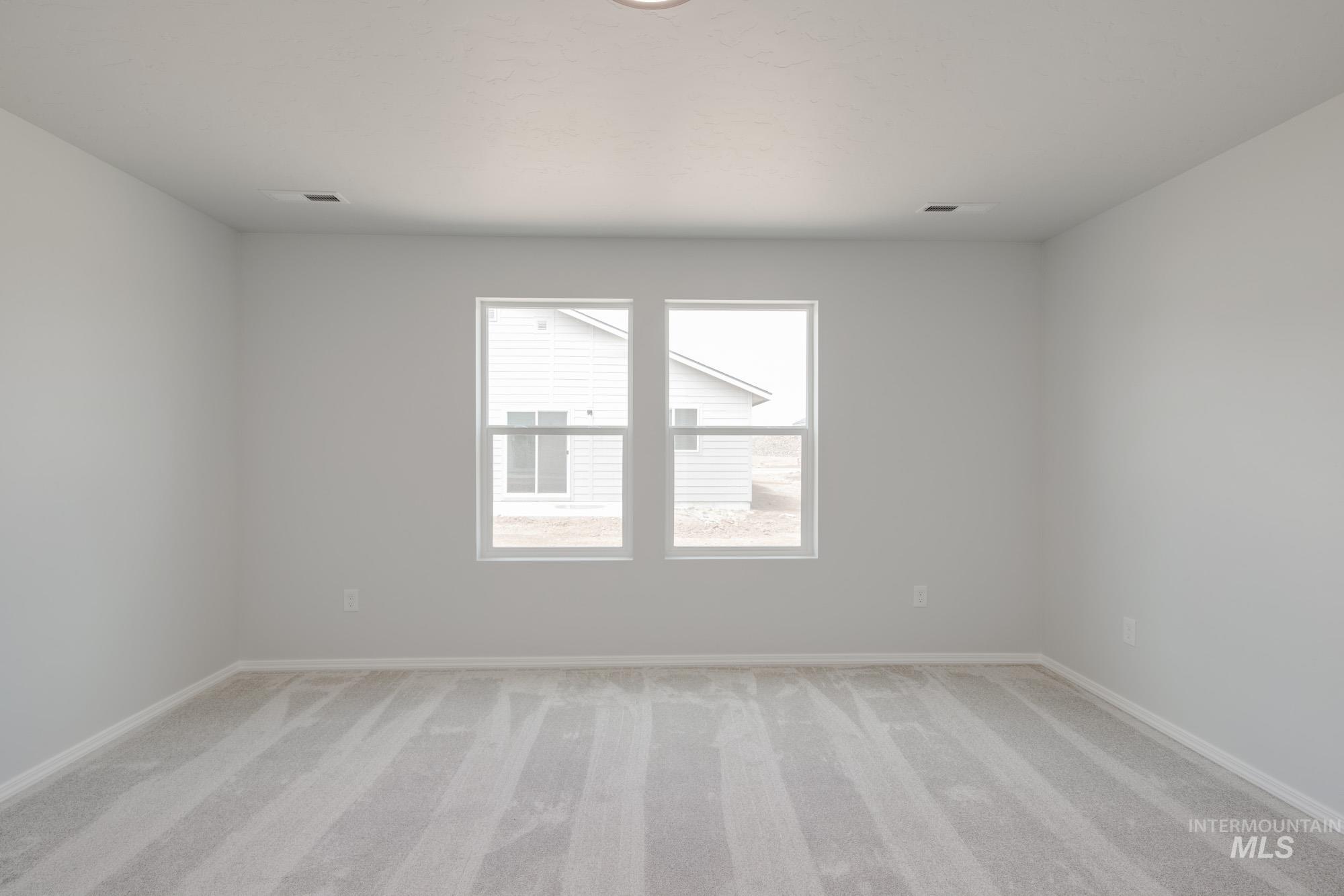 Spare room with light colored carpet and baseboards