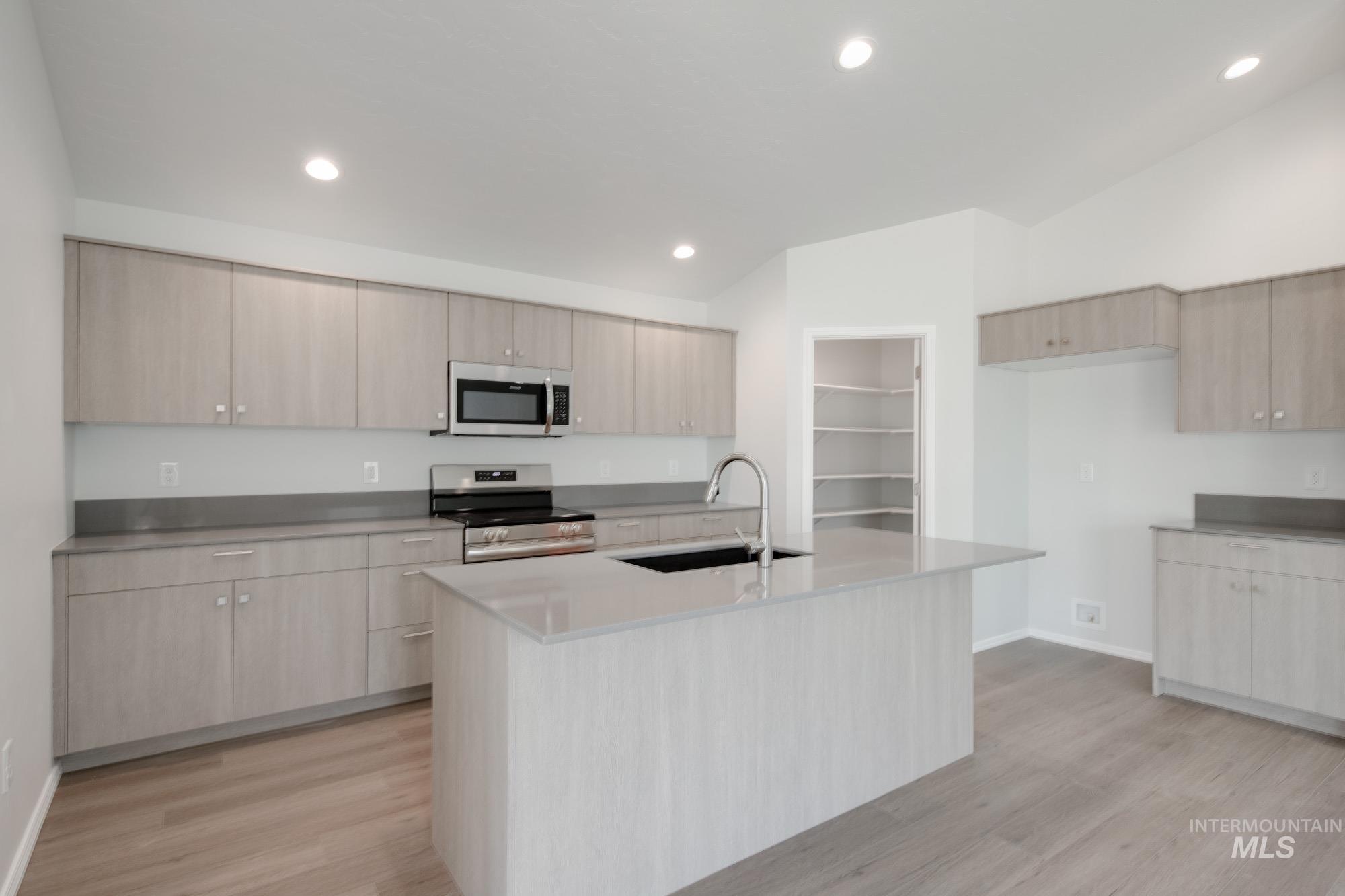 Kitchen with appliances with stainless steel finishes, recessed lighting, light wood-style floors, modern cabinets, and light stone counters