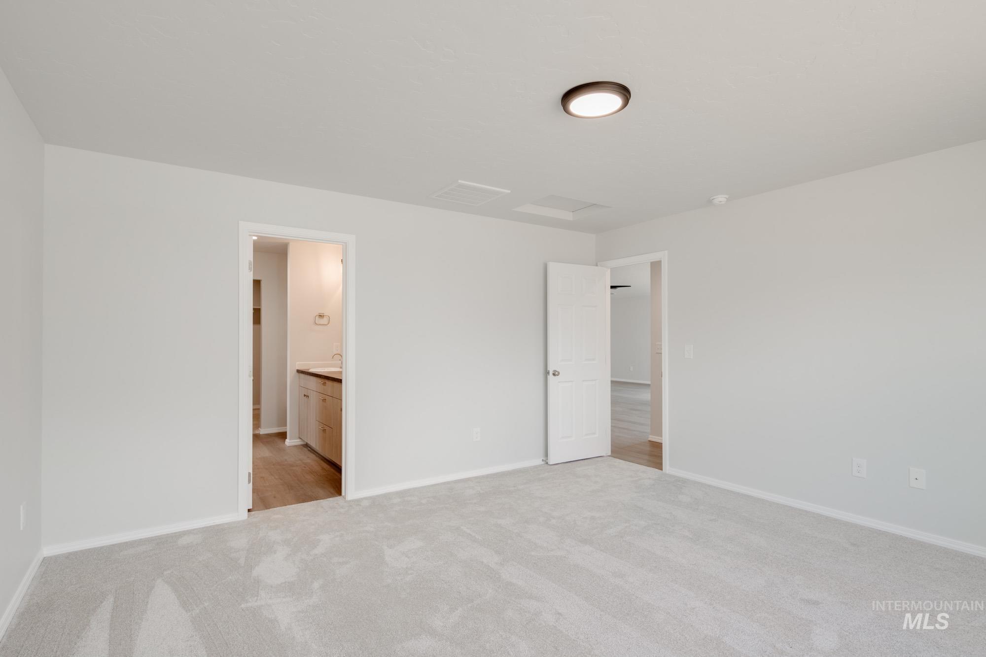 Unfurnished bedroom featuring light carpet and ensuite bath