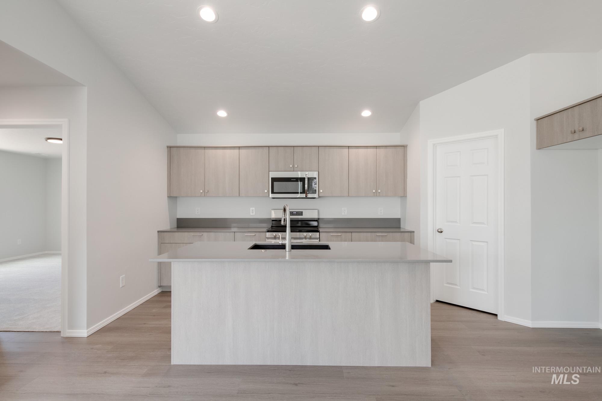 Kitchen featuring an island with sink, modern cabinets, stainless steel appliances, light wood-style floors, and recessed lighting
