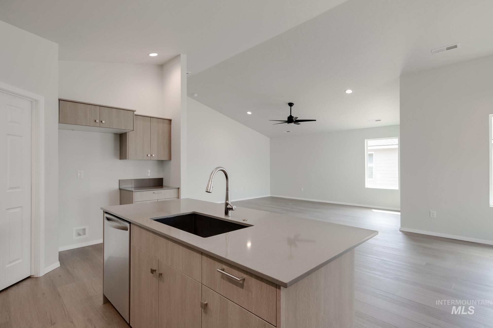 Kitchen with light brown cabinets, light wood-style flooring, a kitchen island with sink, recessed lighting, and stainless steel dishwasher