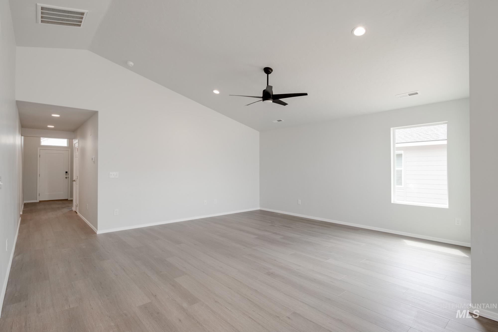 Empty room with lofted ceiling, recessed lighting, and light wood finished floors