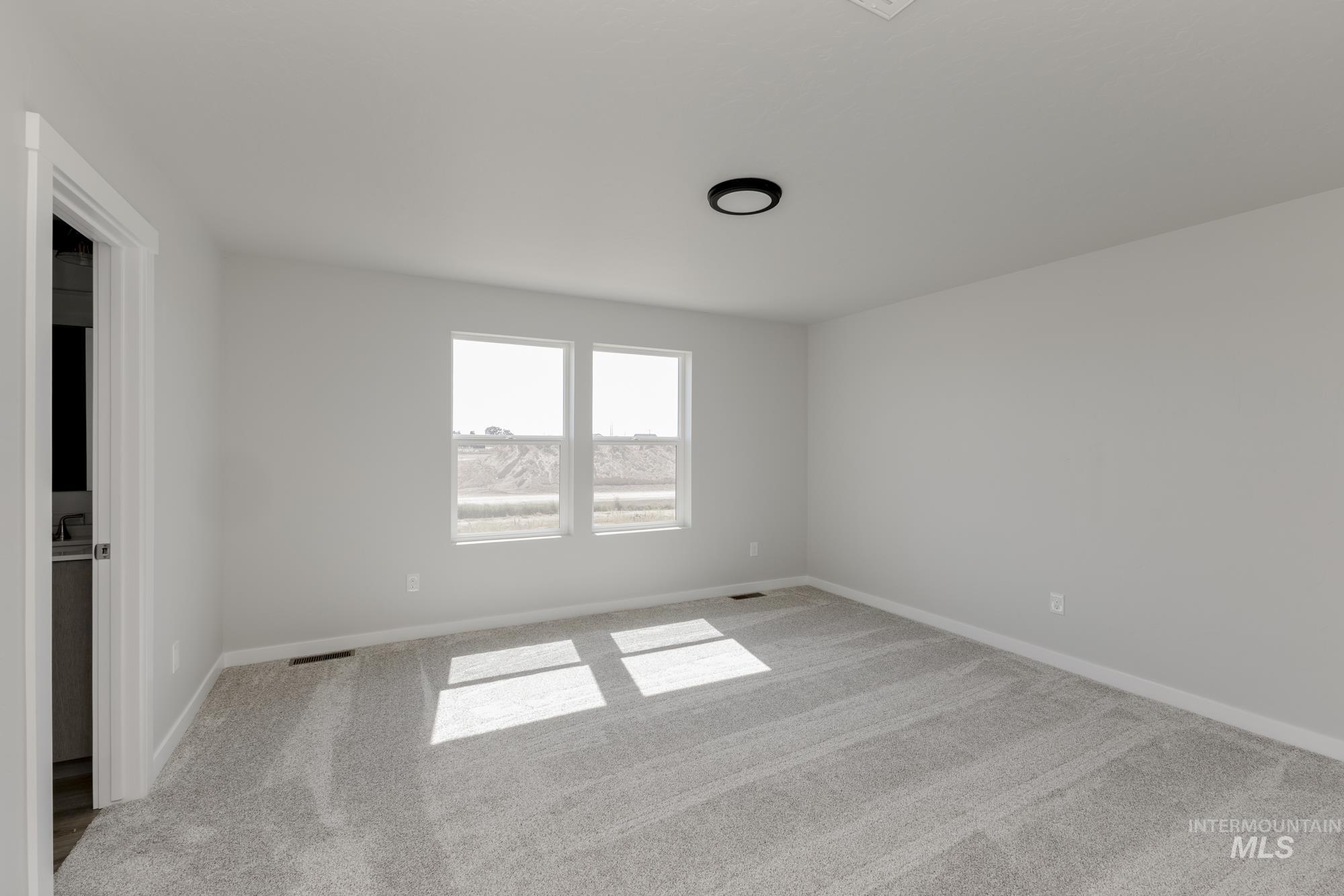 Unfurnished room featuring light carpet and baseboards