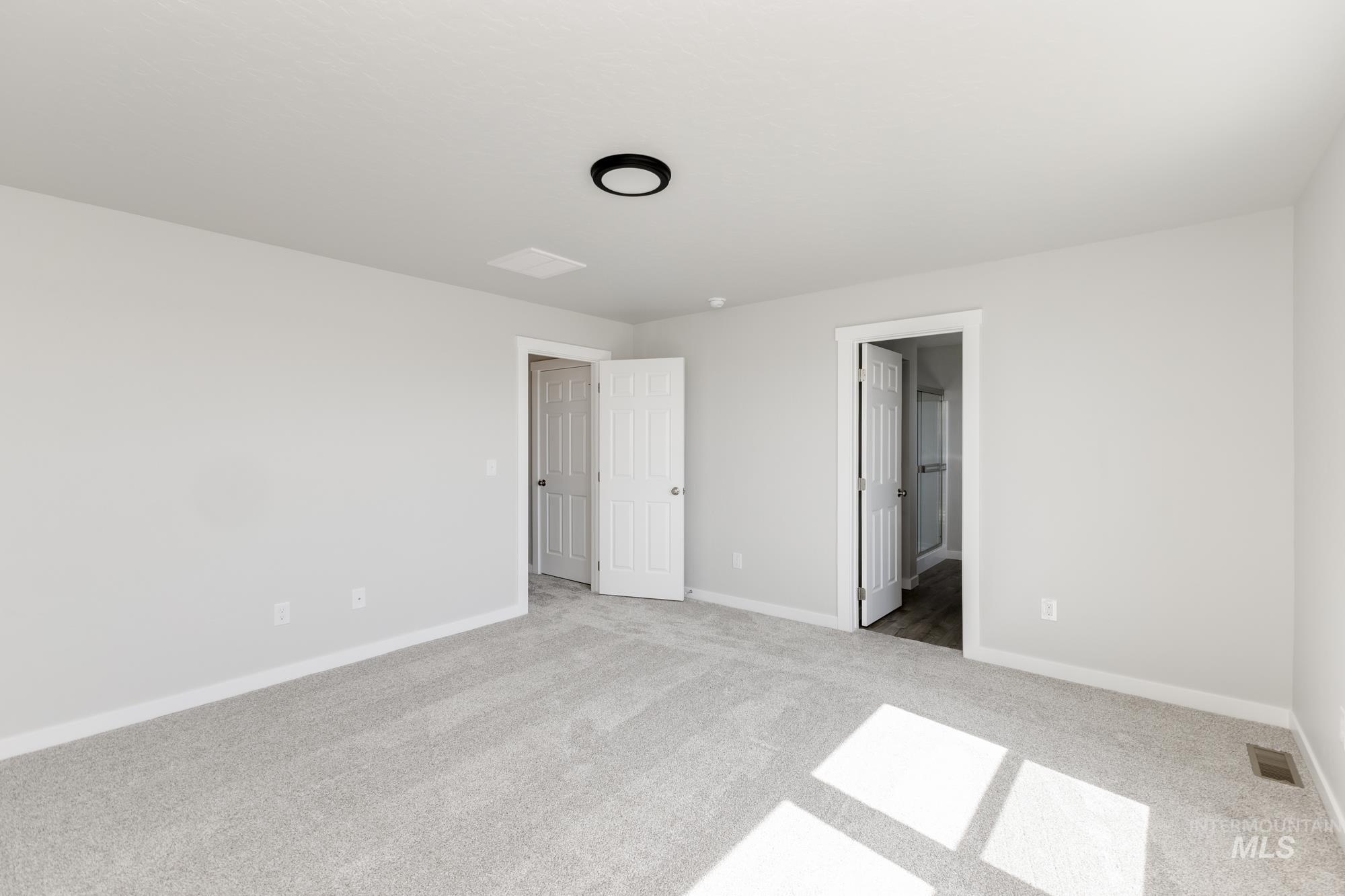 Unfurnished bedroom with light carpet and ensuite bathroom