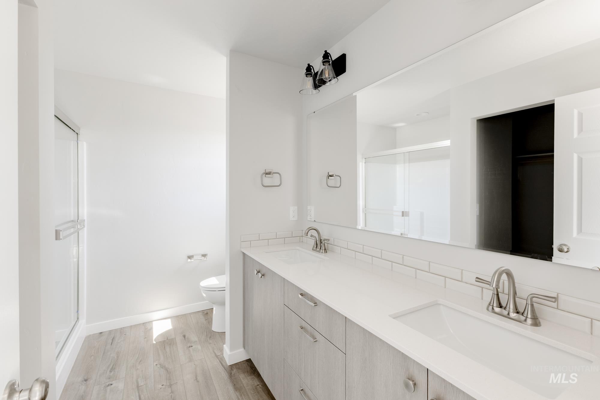 Bathroom with a shower stall, double vanity, and light wood finished floors