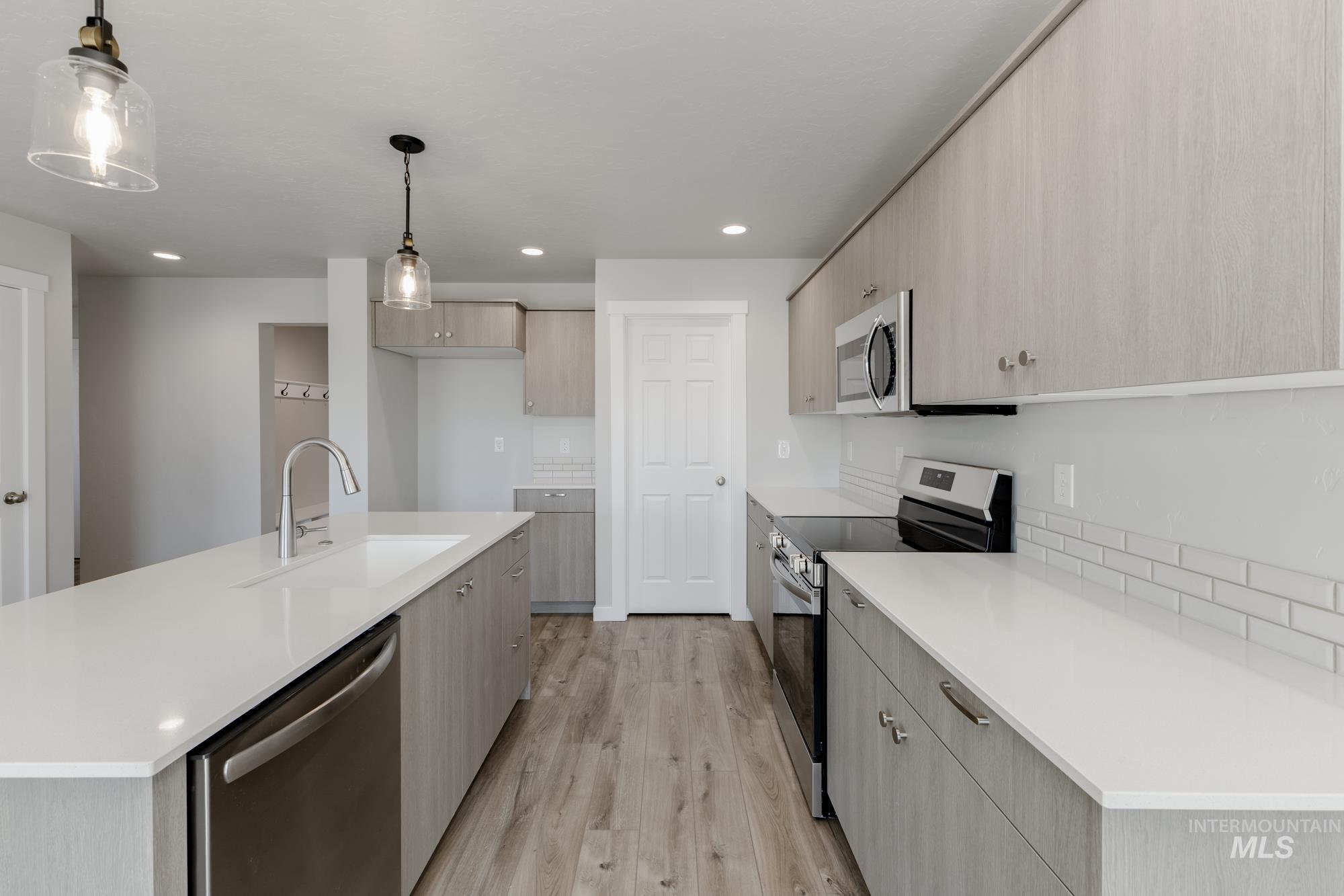 Kitchen with stainless steel appliances, modern cabinets, light wood-style flooring, pendant lighting, and recessed lighting