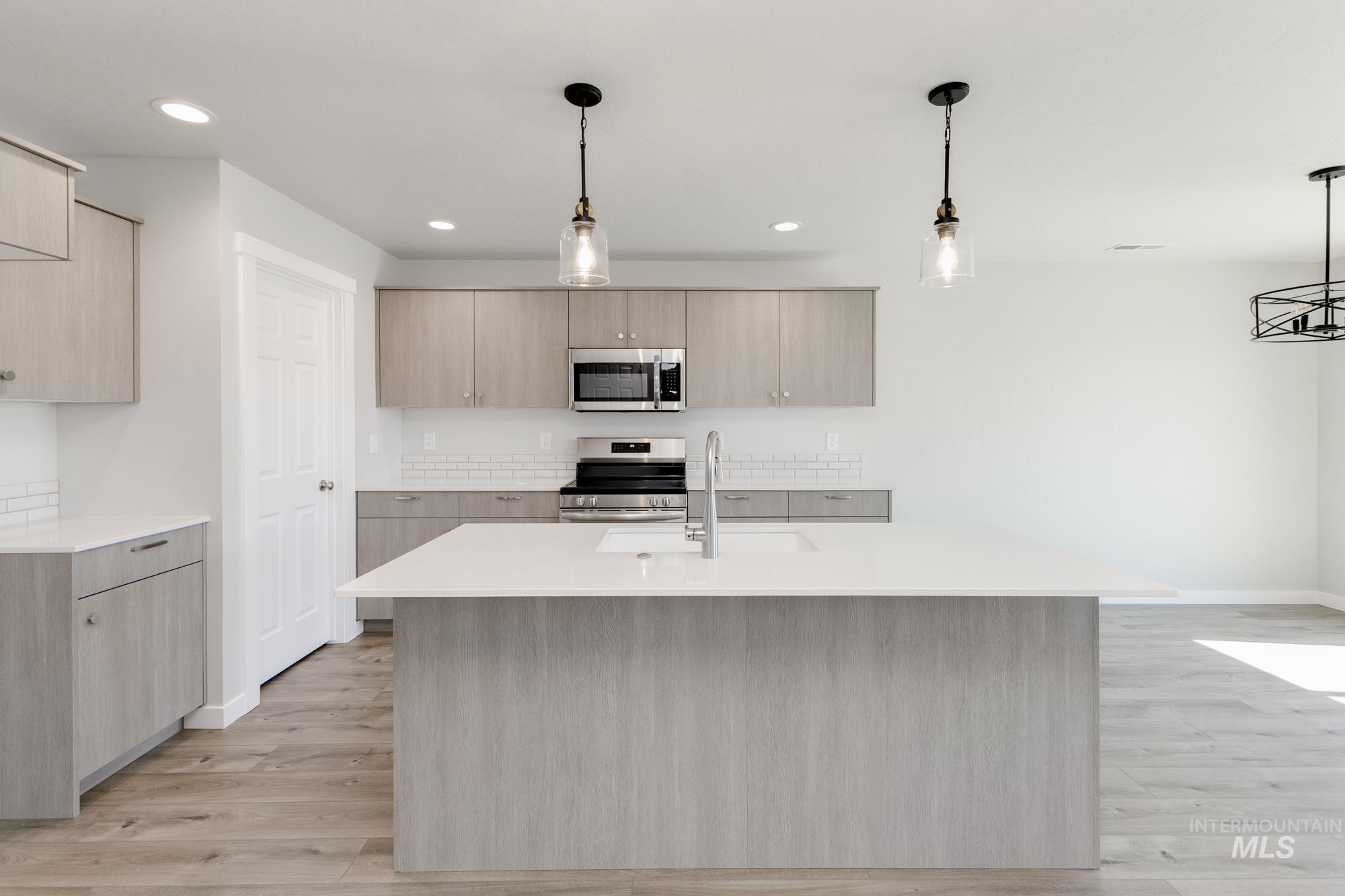 Kitchen featuring light brown cabinets, hanging light fixtures, light wood finished floors, and recessed lighting