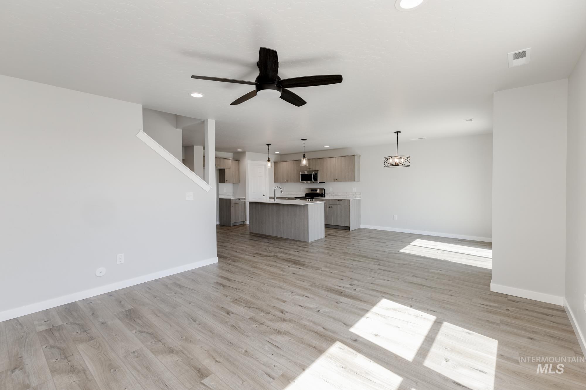 Unfurnished living room featuring a ceiling fan, light wood-style flooring, and recessed lighting