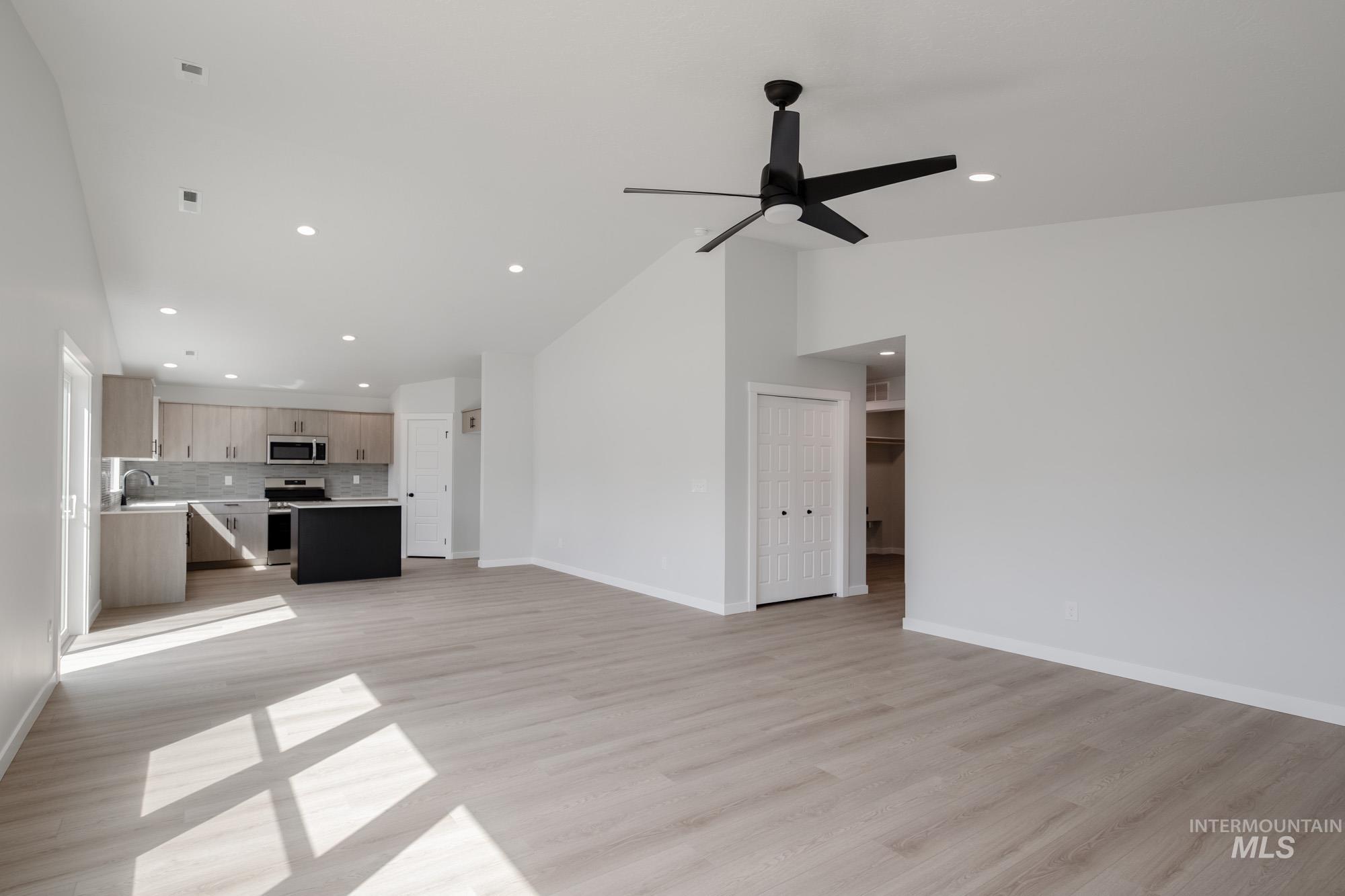 Unfurnished living room featuring light wood-type flooring, recessed lighting, and vaulted ceiling