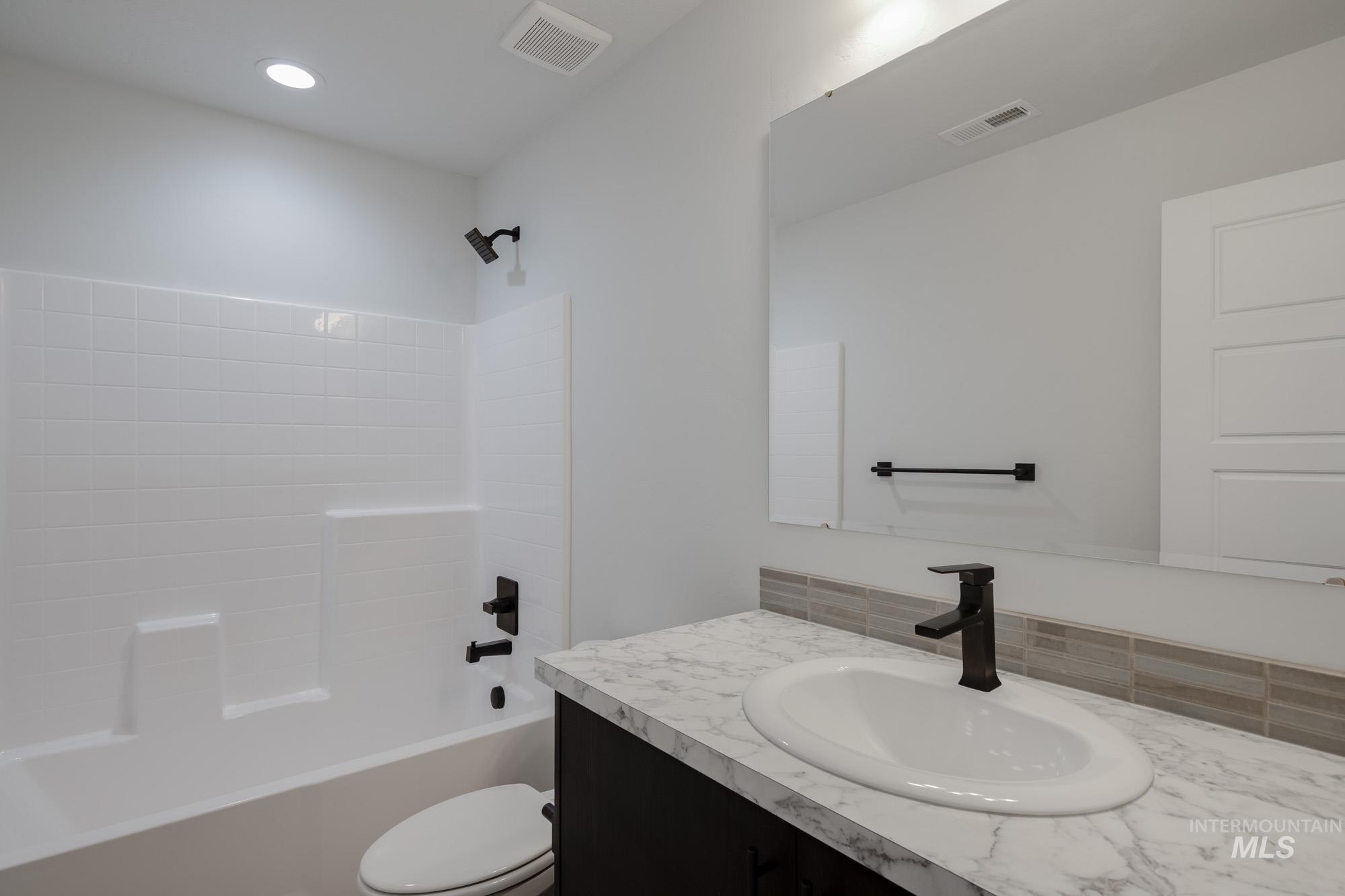 Bathroom featuring vanity, bathtub / shower combination, recessed lighting, and tasteful backsplash