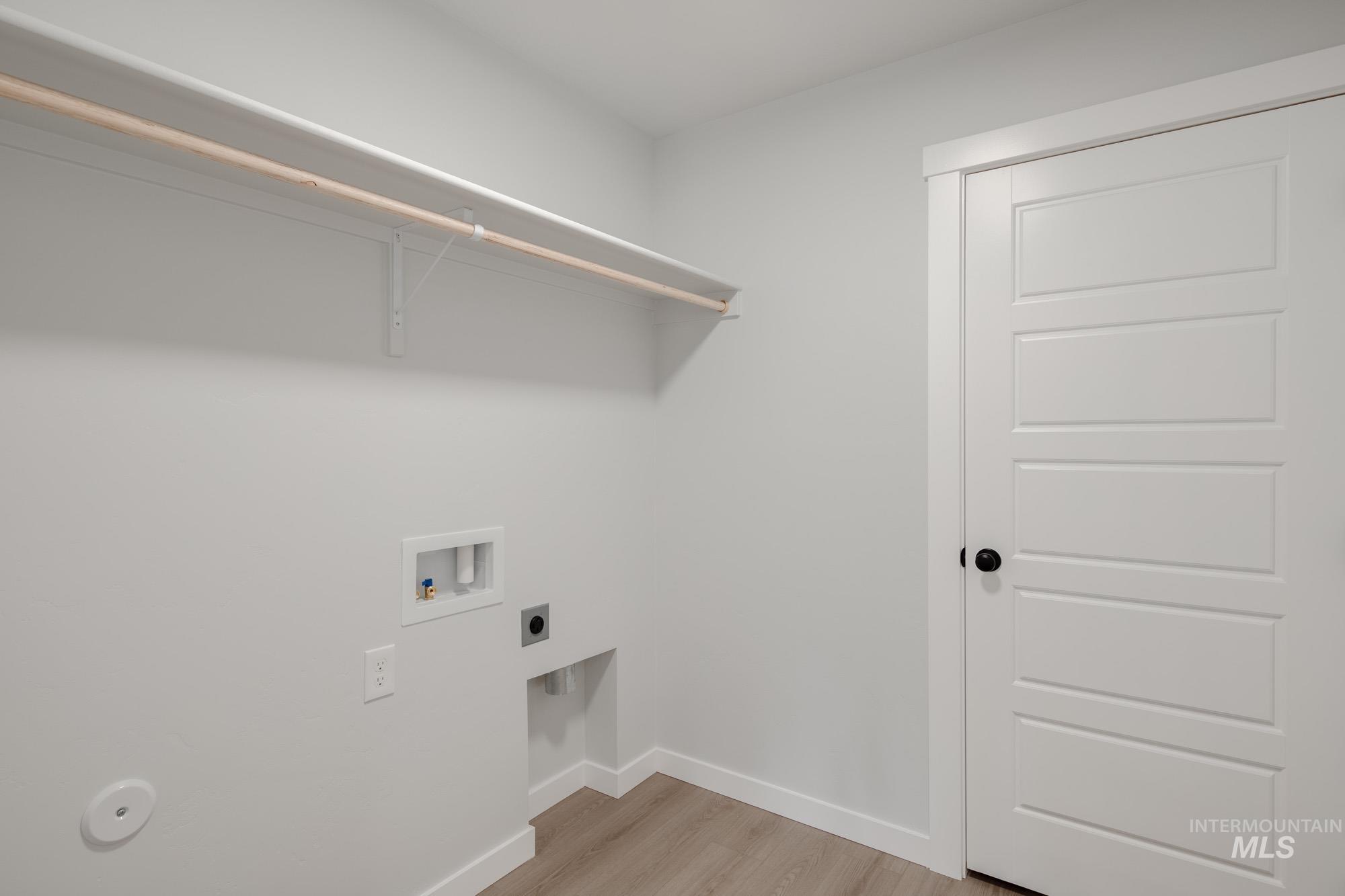 Washroom with light wood-type flooring, washer hookup, and electric dryer hookup