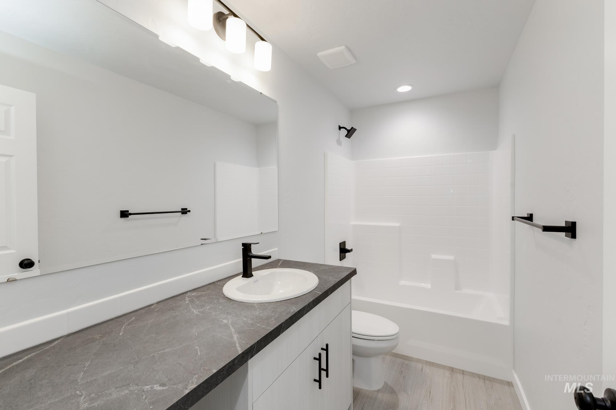 Full bath featuring vanity,  shower combination, light wood-type flooring, and recessed lighting