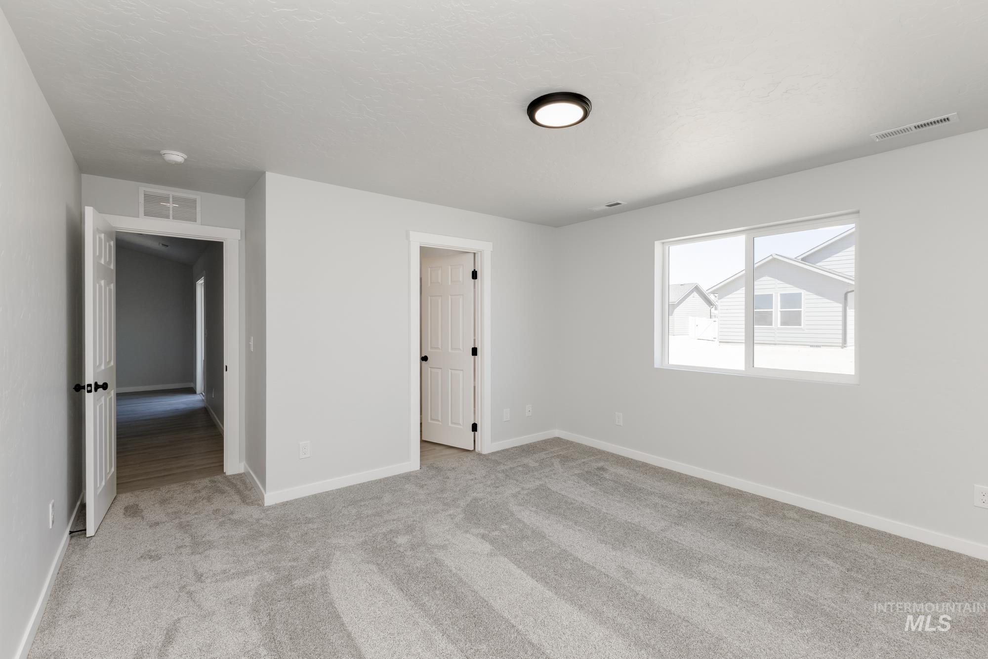 Unfurnished bedroom with light colored carpet and baseboards