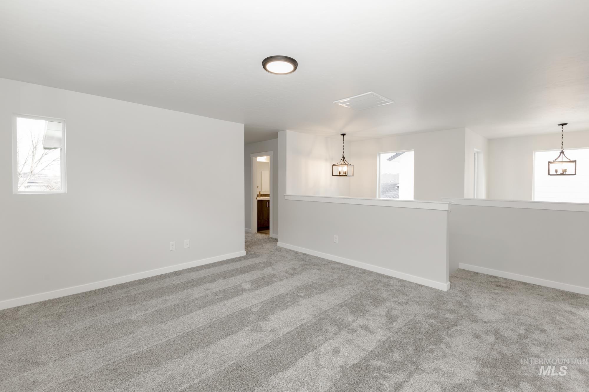 Unfurnished room featuring light colored carpet and a chandelier