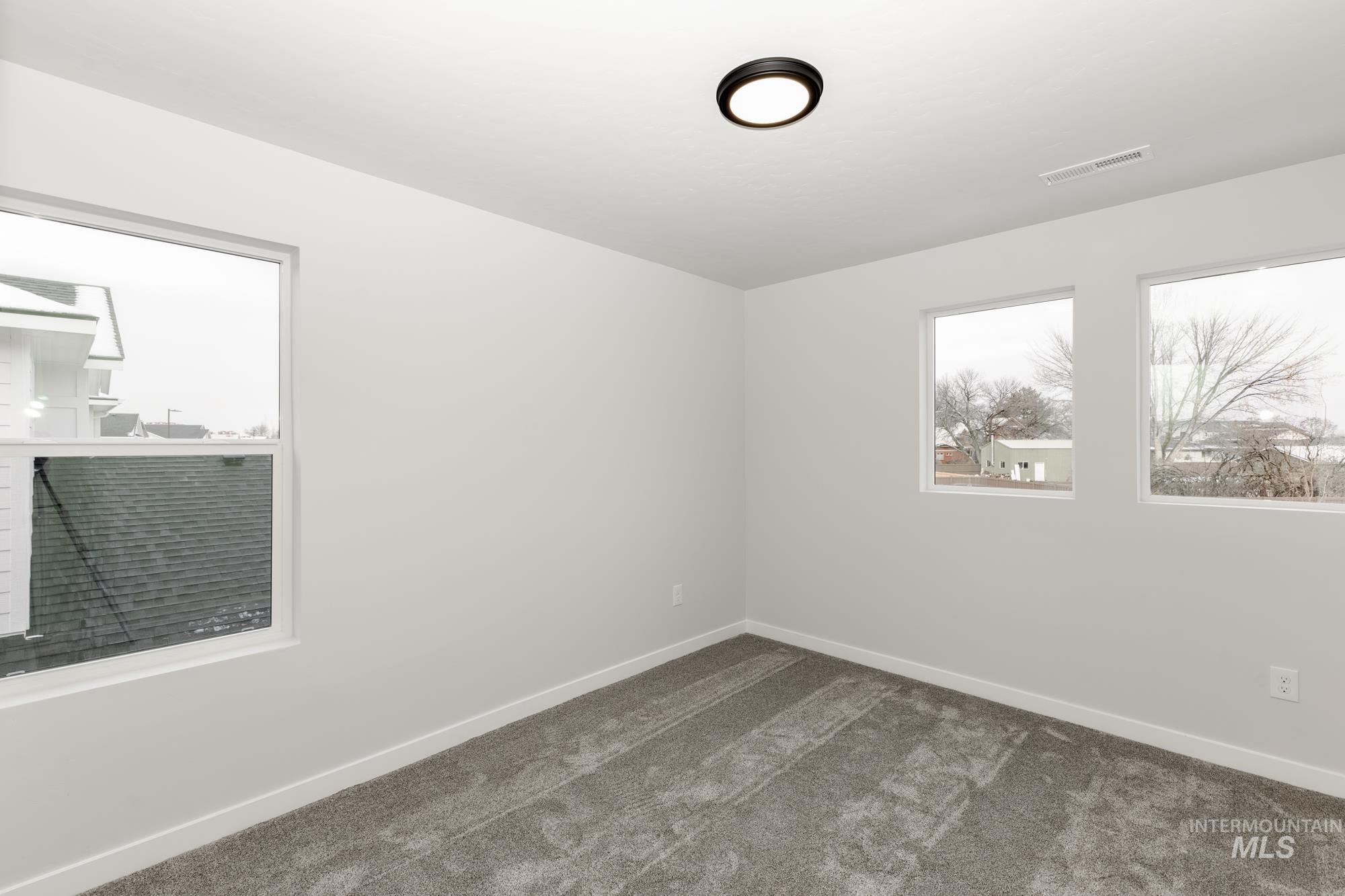 Unfurnished room featuring dark carpet and baseboards