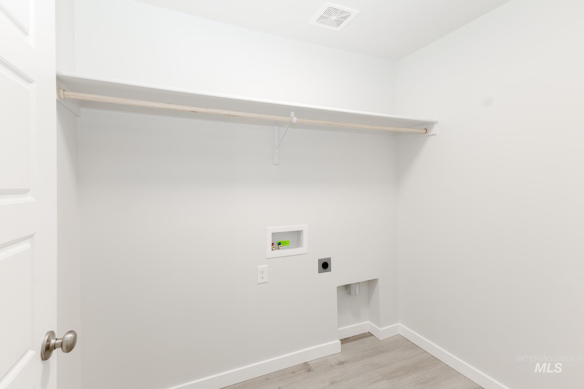 Laundry room with electric dryer hookup, hookup for a washing machine, and light wood-style flooring