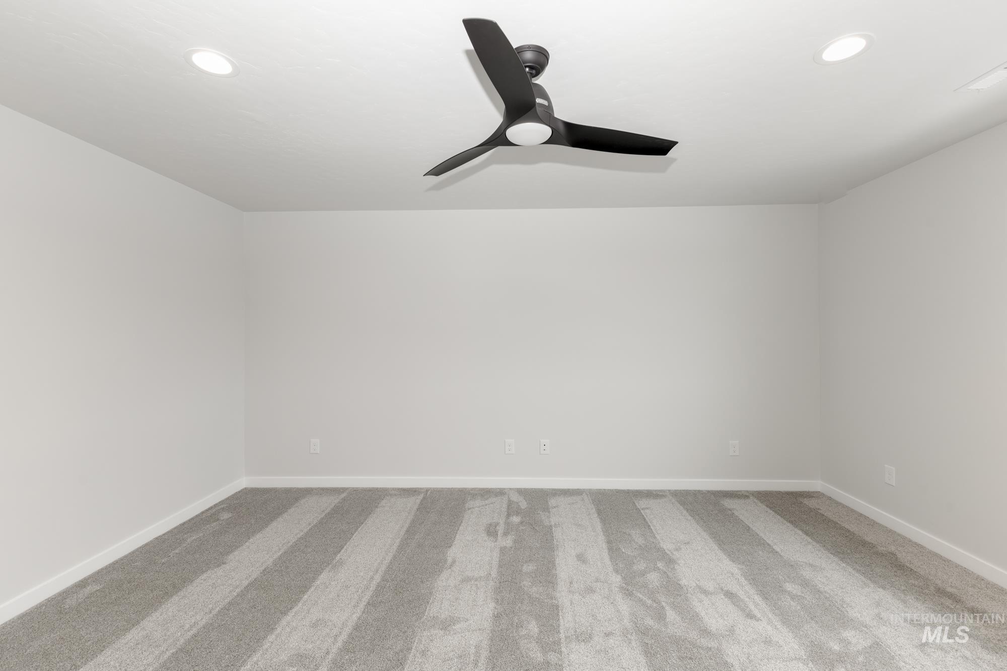 Carpeted empty room with a ceiling fan and recessed lighting