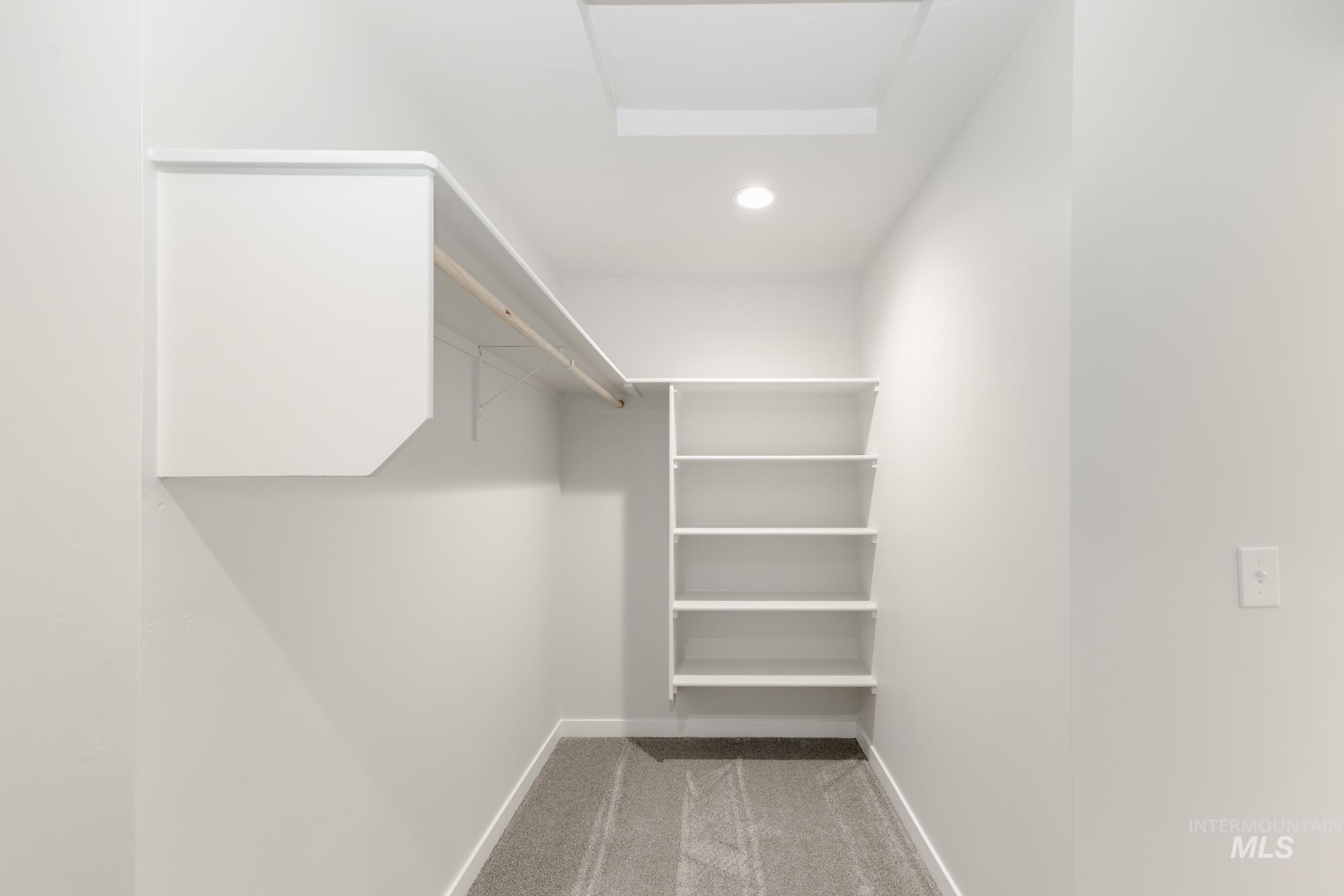 Walk in closet featuring light carpet and attic access