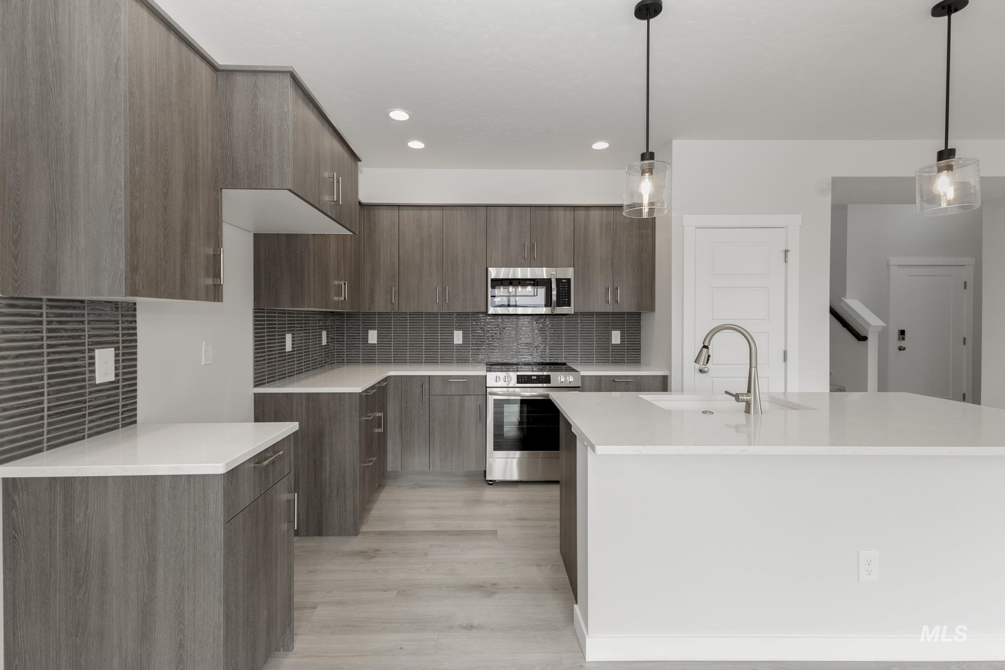 Kitchen featuring modern cabinets, stainless steel appliances, light stone countertops, decorative light fixtures, and recessed lighting