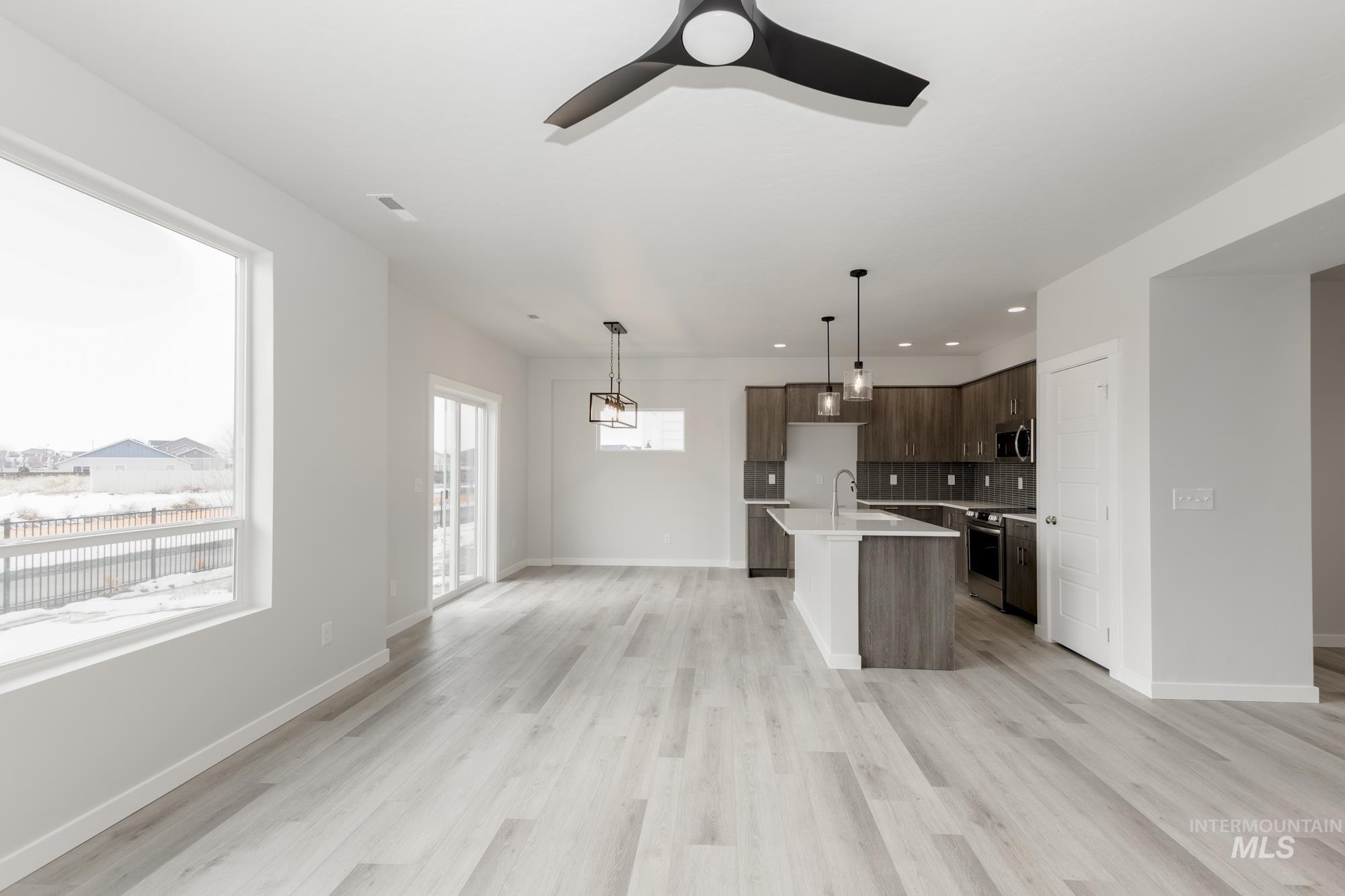 Kitchen featuring tasteful backsplash, an island with sink, dark brown cabinets, light wood-style floors, and recessed lighting