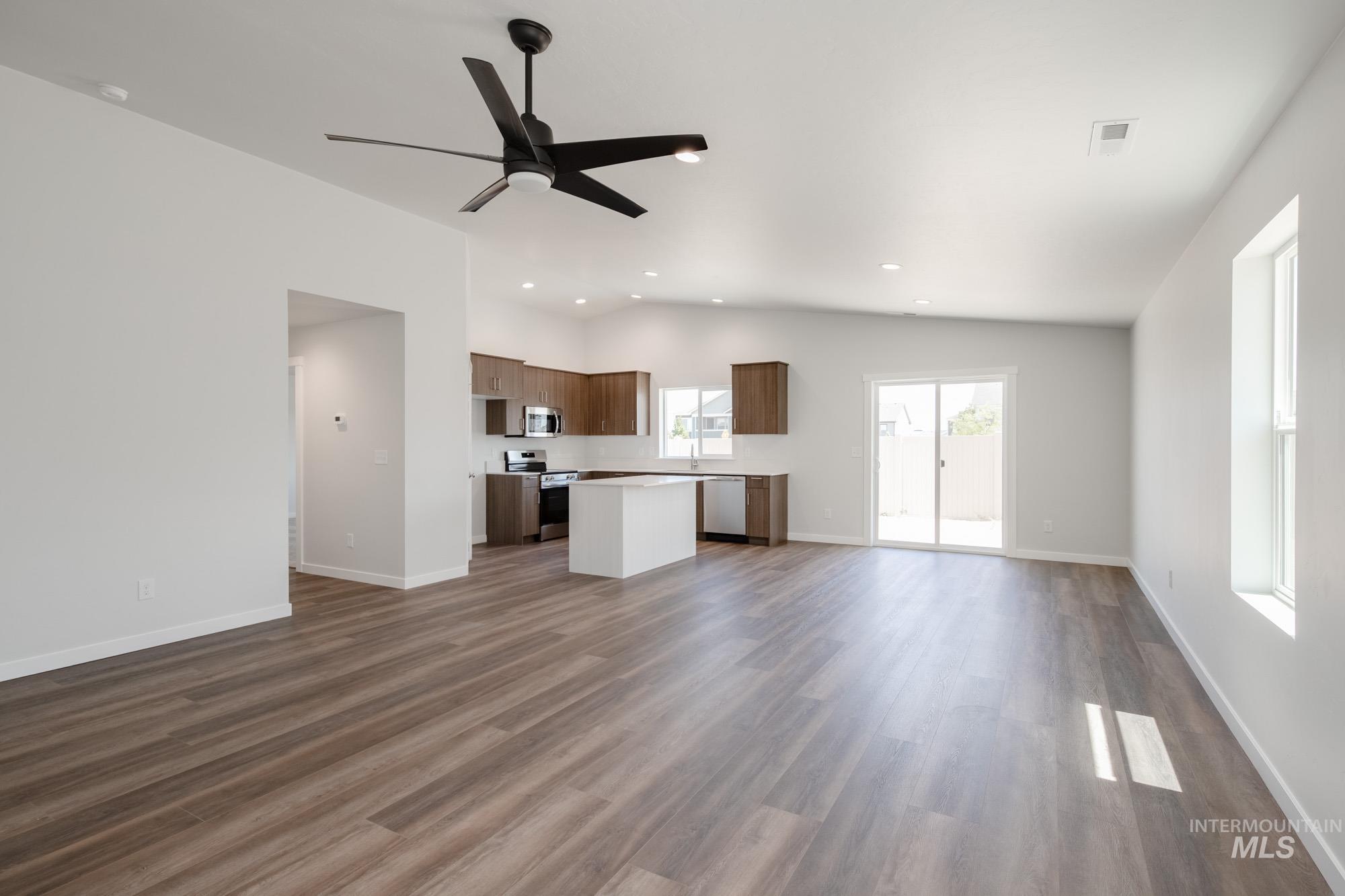 Unfurnished living room with dark wood-type flooring, ceiling fan, lofted ceiling, and recessed lighting