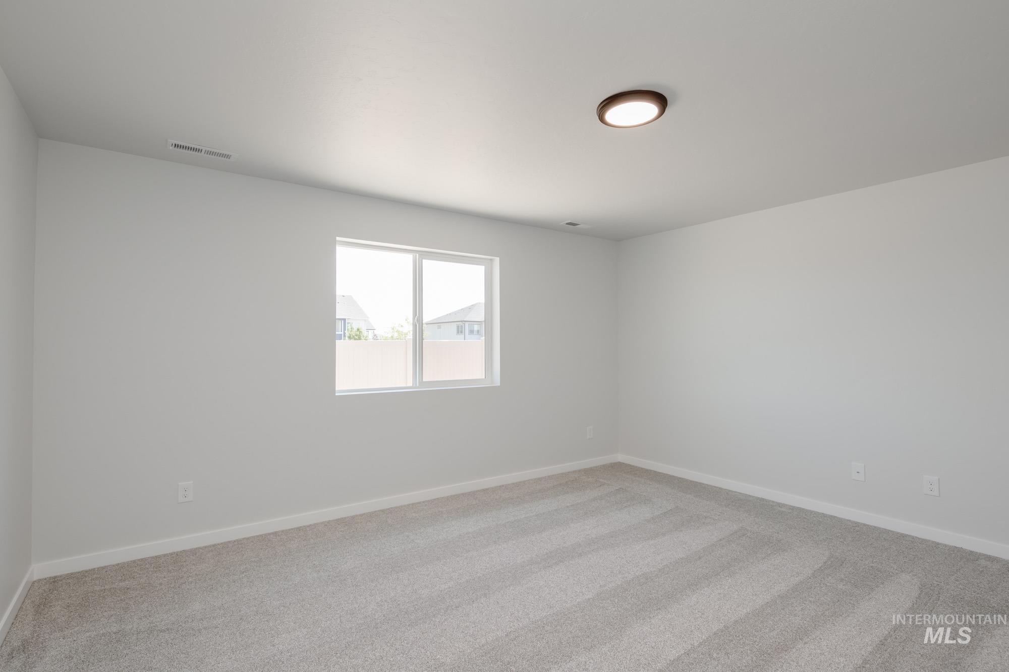 Empty room featuring light colored carpet and baseboards
