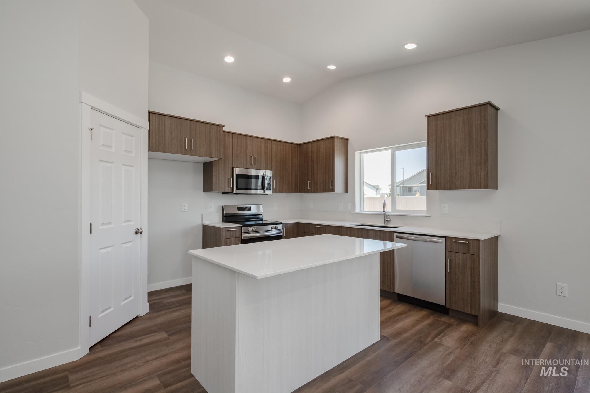 Kitchen with stainless steel appliances, a kitchen island, modern cabinets, recessed lighting, and dark wood finished floors