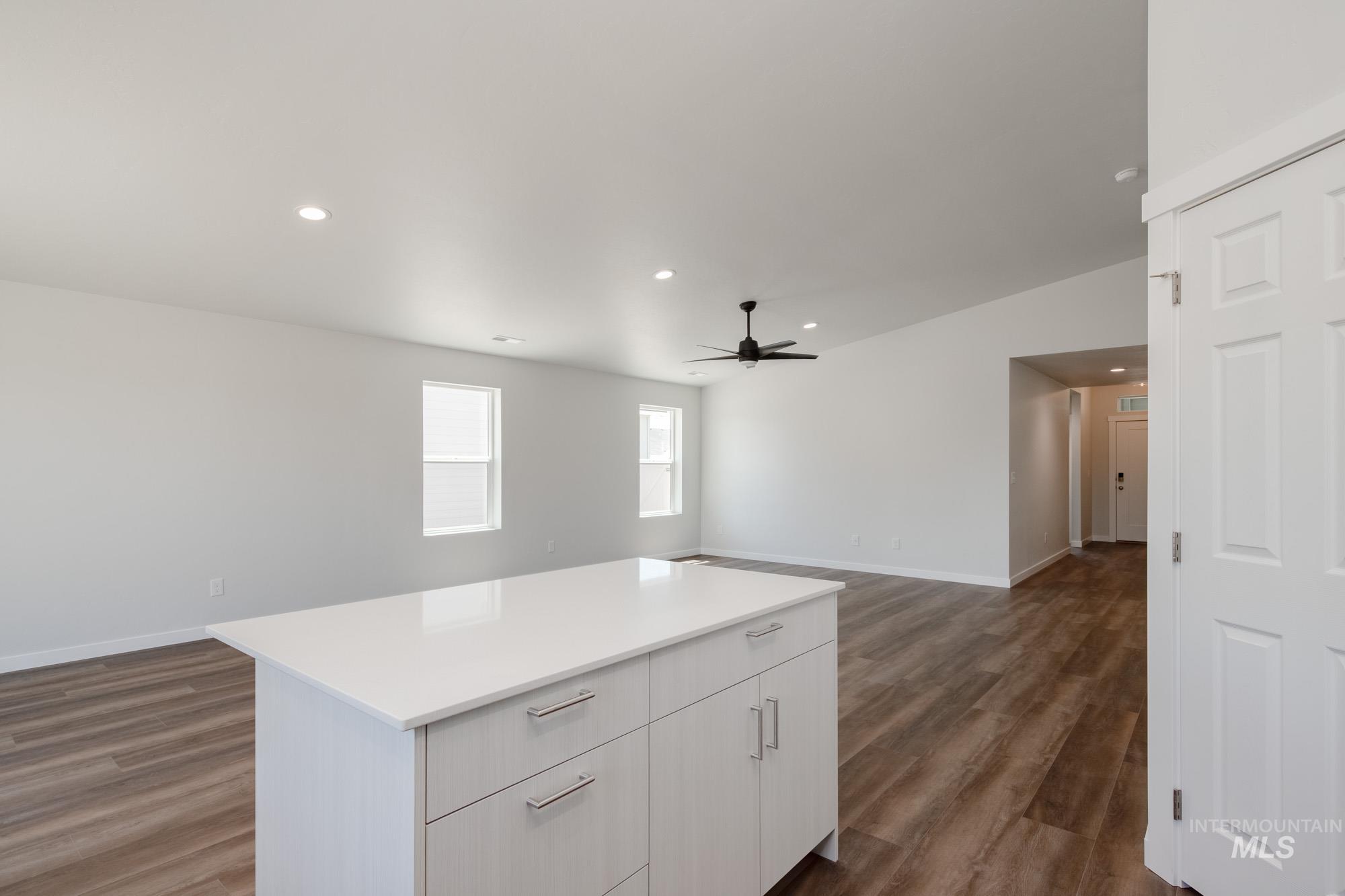 Kitchen with dark wood-style flooring, recessed lighting, light countertops, white cabinets, and open floor plan