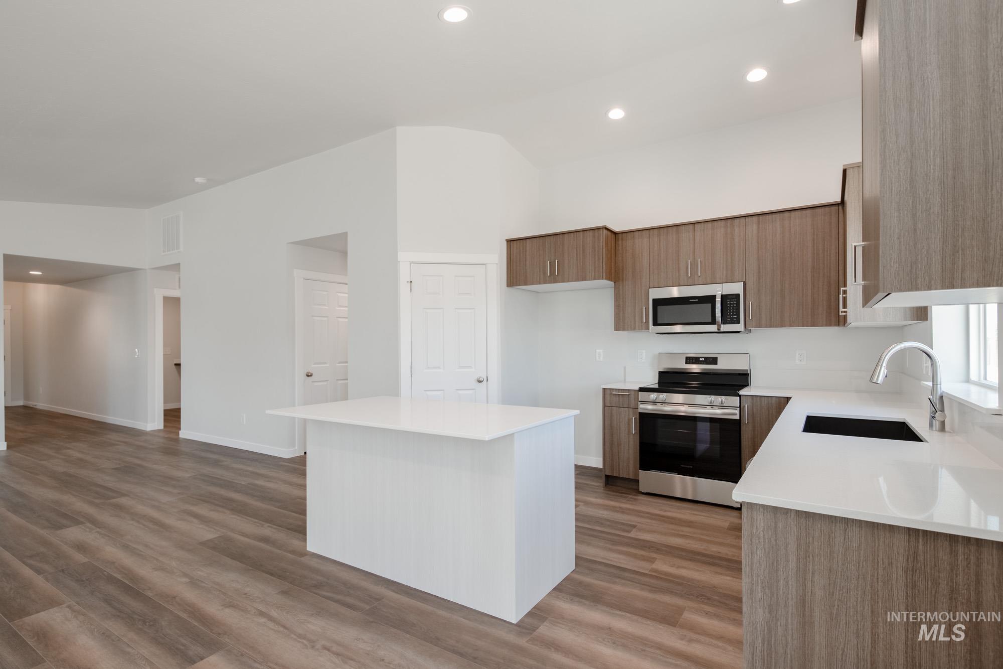 Kitchen with appliances with stainless steel finishes, modern cabinets, a kitchen island, recessed lighting, and light stone counters