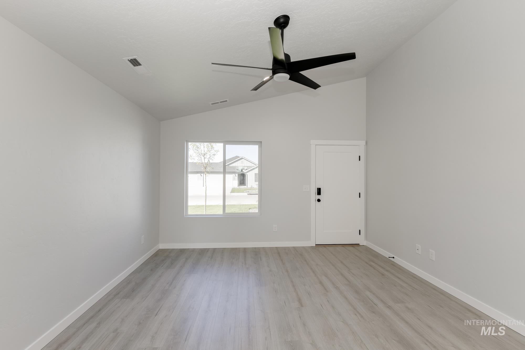 Unfurnished room with light wood-style flooring, lofted ceiling, and ceiling fan