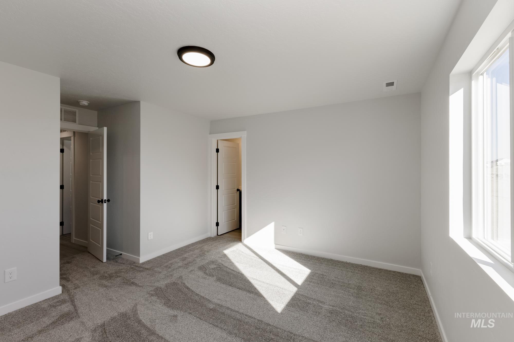 Unfurnished bedroom with light carpet and baseboards