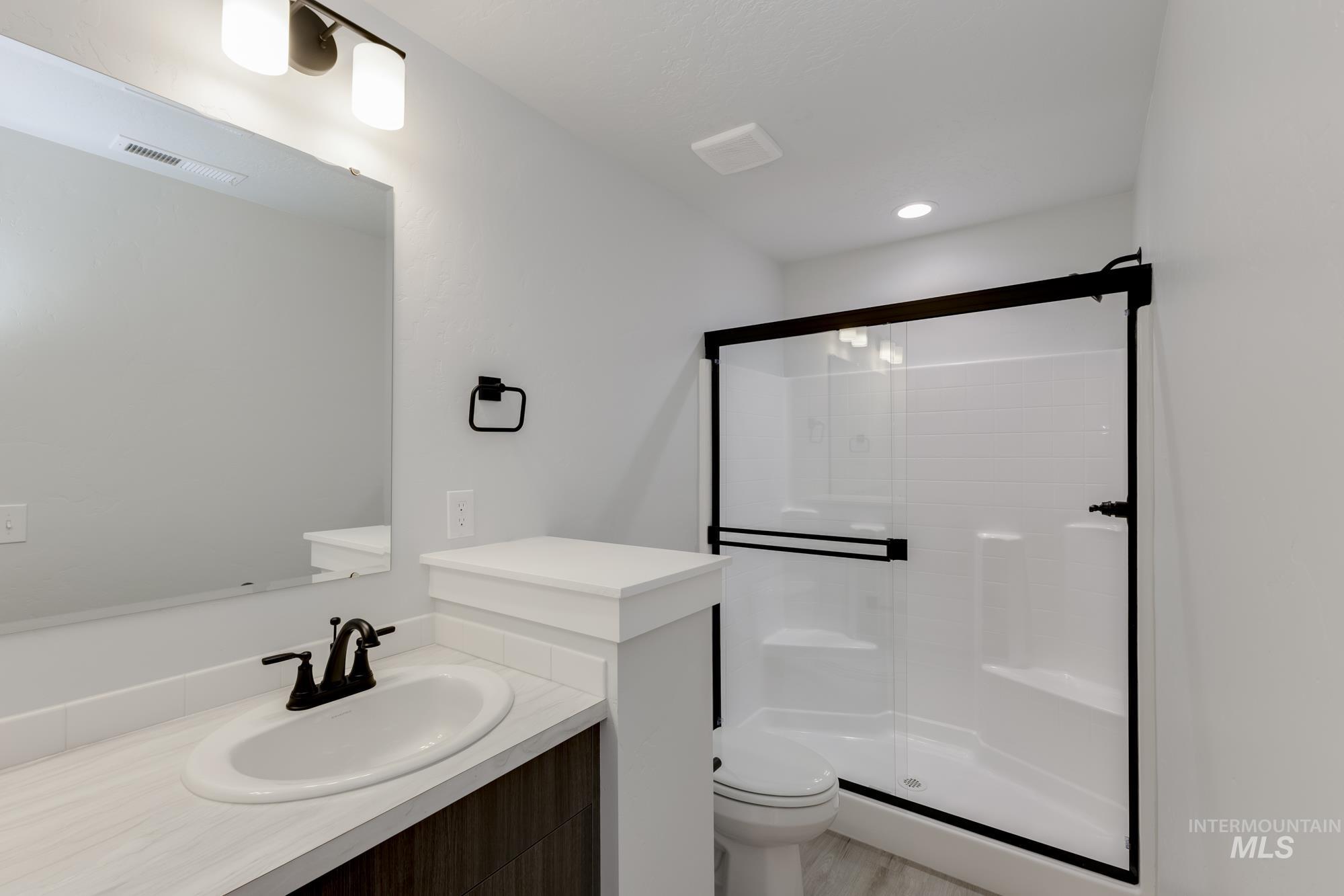 Full bath with a shower stall, vanity, and recessed lighting