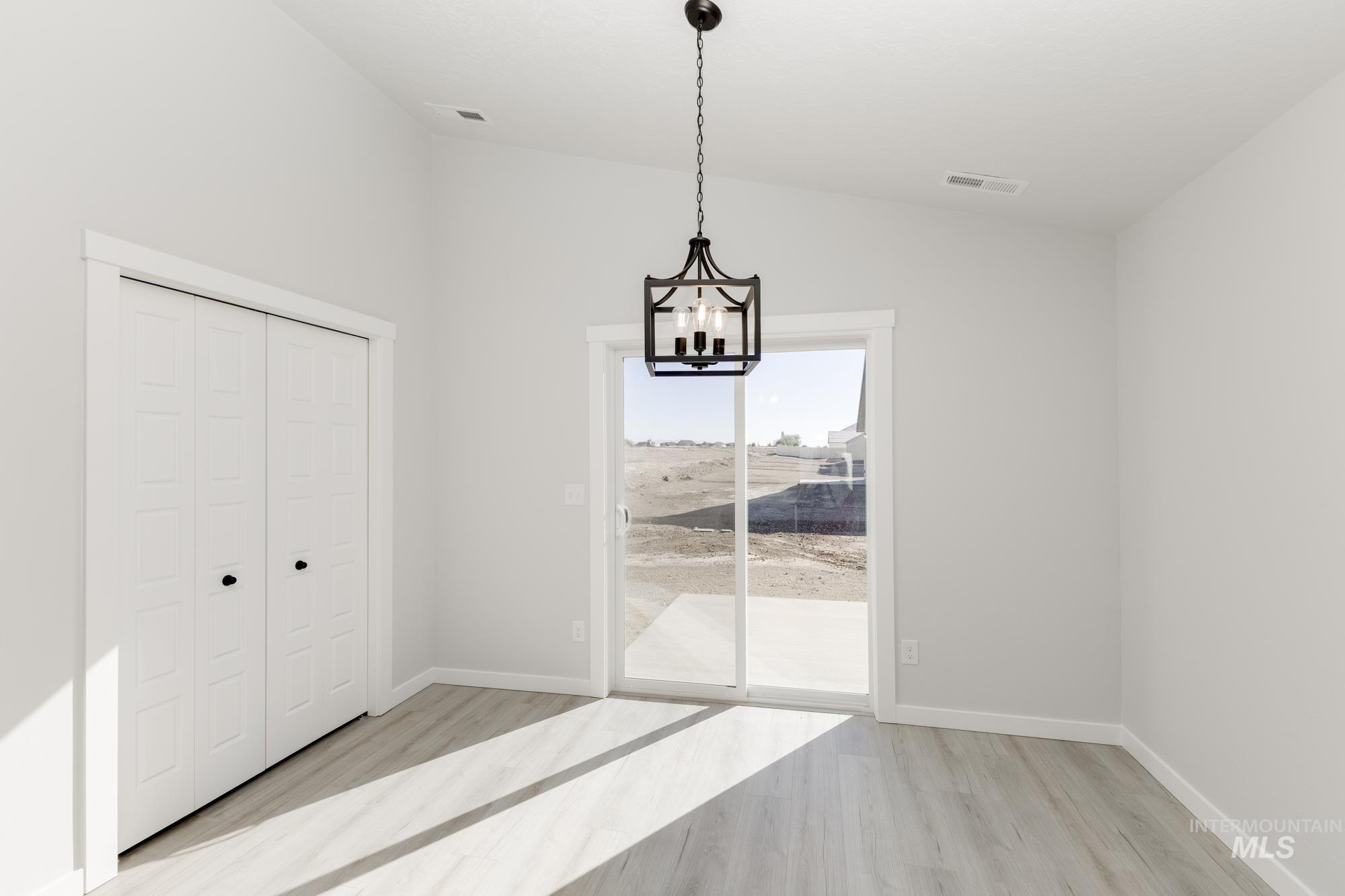 Unfurnished dining area with light wood finished floors, lofted ceiling, and a chandelier