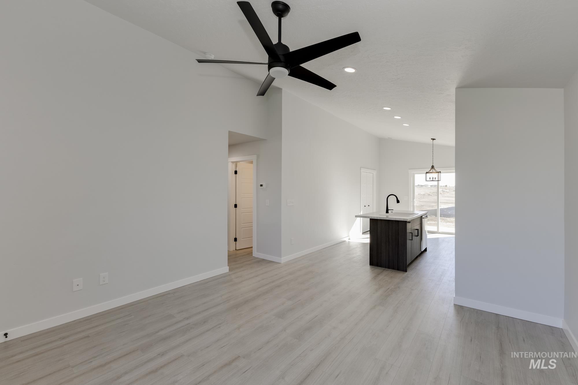 Unfurnished living room with light wood finished floors, ceiling fan, high vaulted ceiling, and recessed lighting