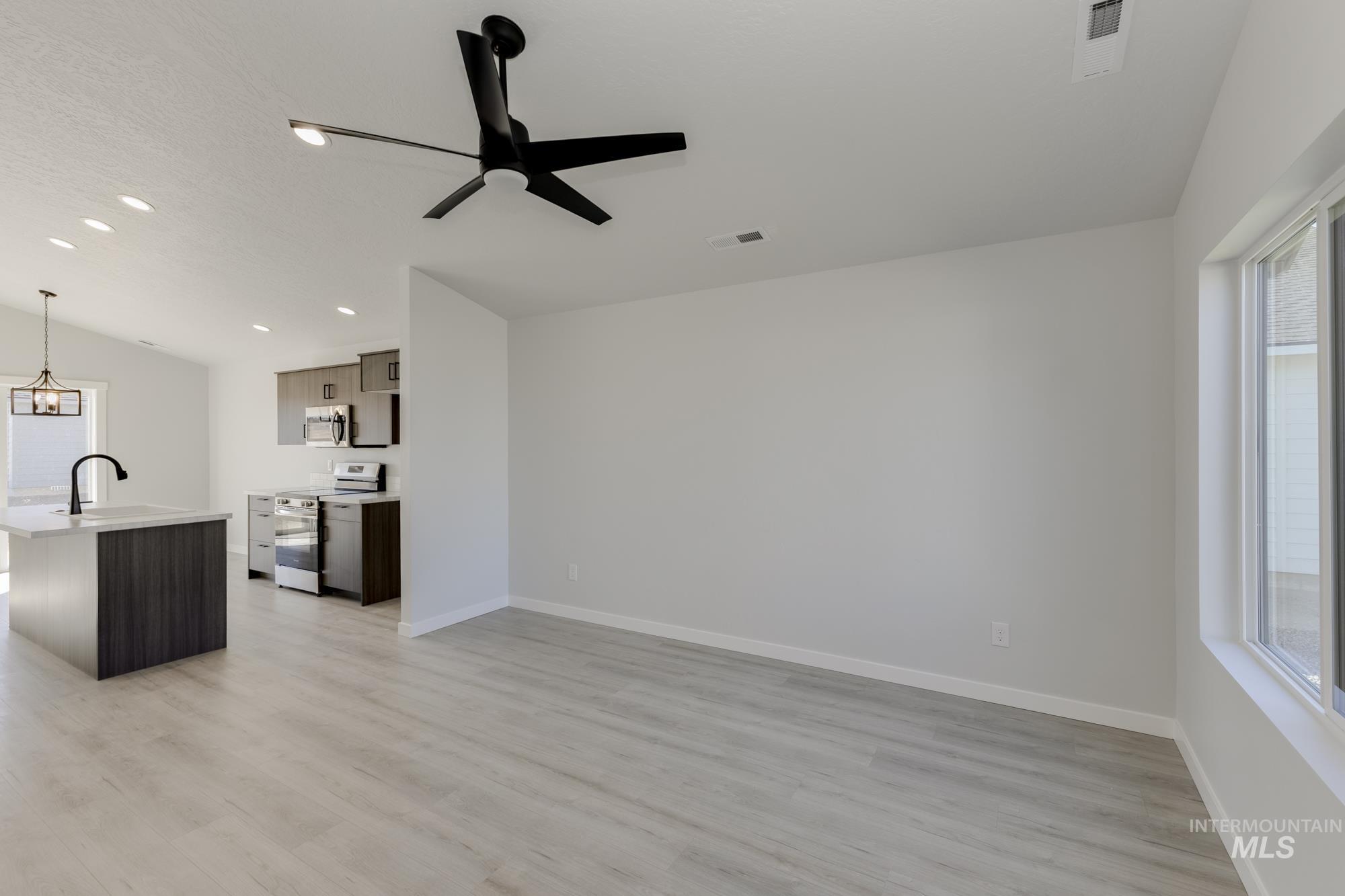Unfurnished living room with vaulted ceiling, light wood-type flooring, a ceiling fan, and recessed lighting