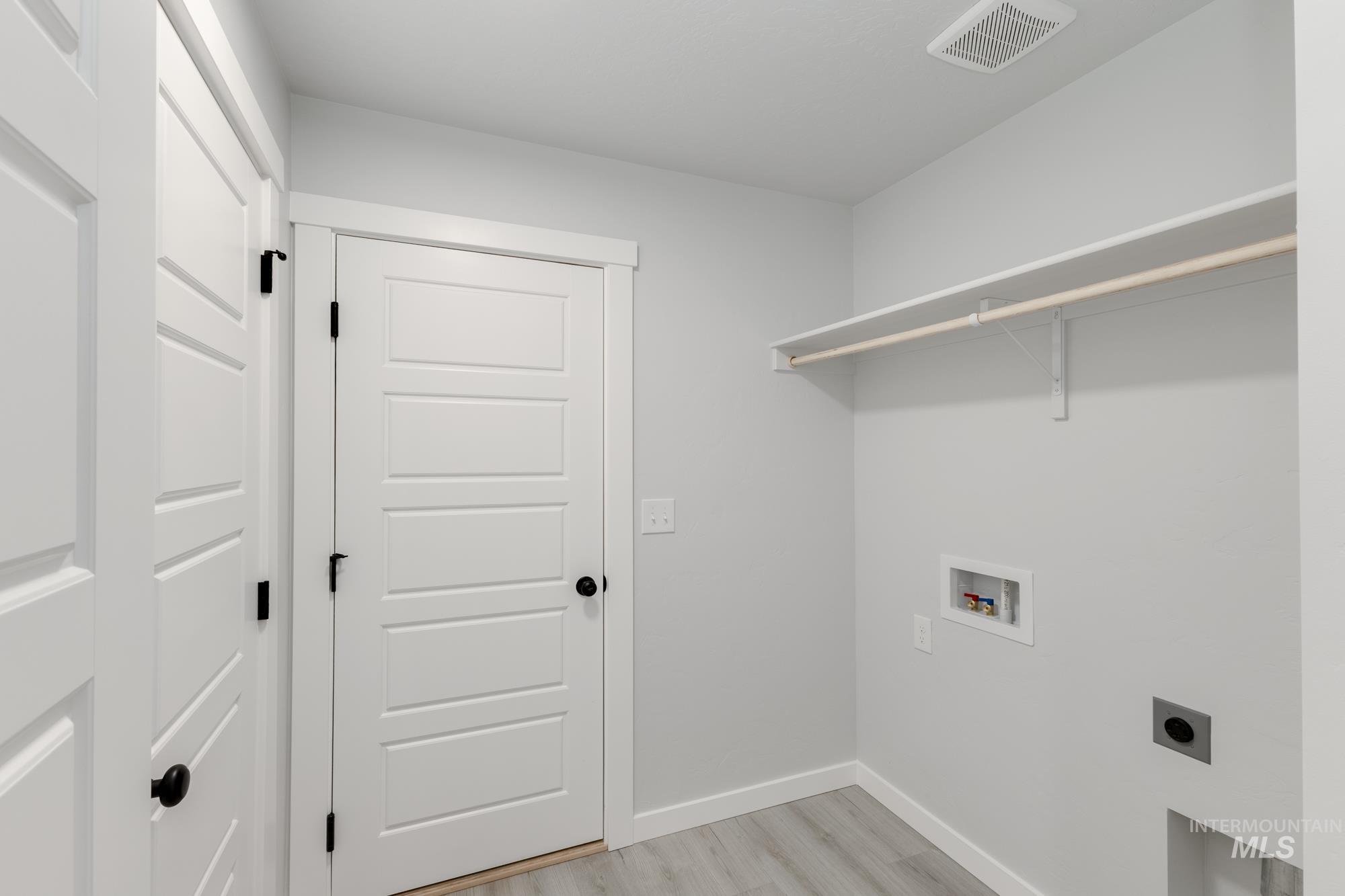 Laundry area with light wood-type flooring, washer hookup, and hookup for an electric dryer
